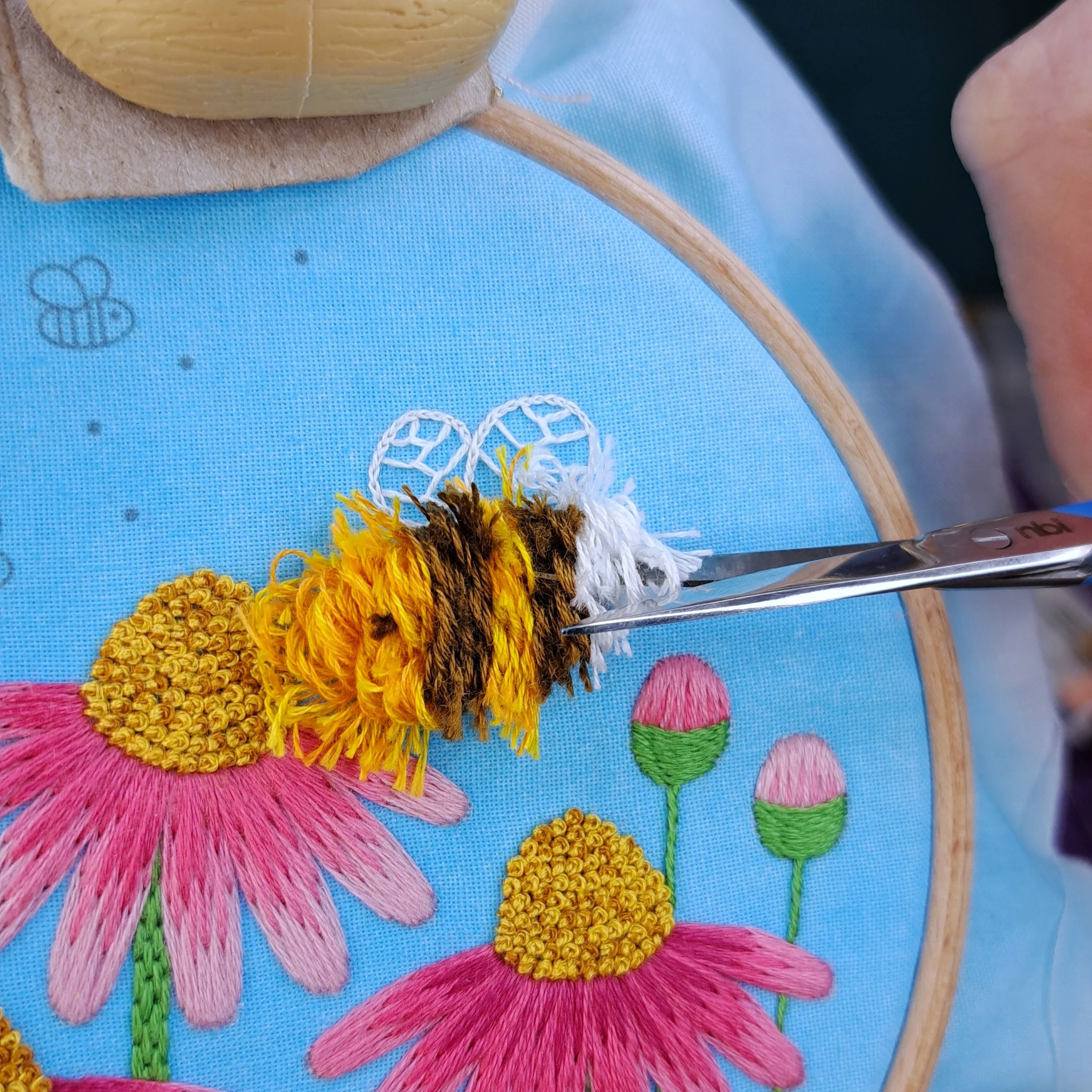 Close-up of the Turkey Stitch loops beginning to be snipped with embroidery scissors.