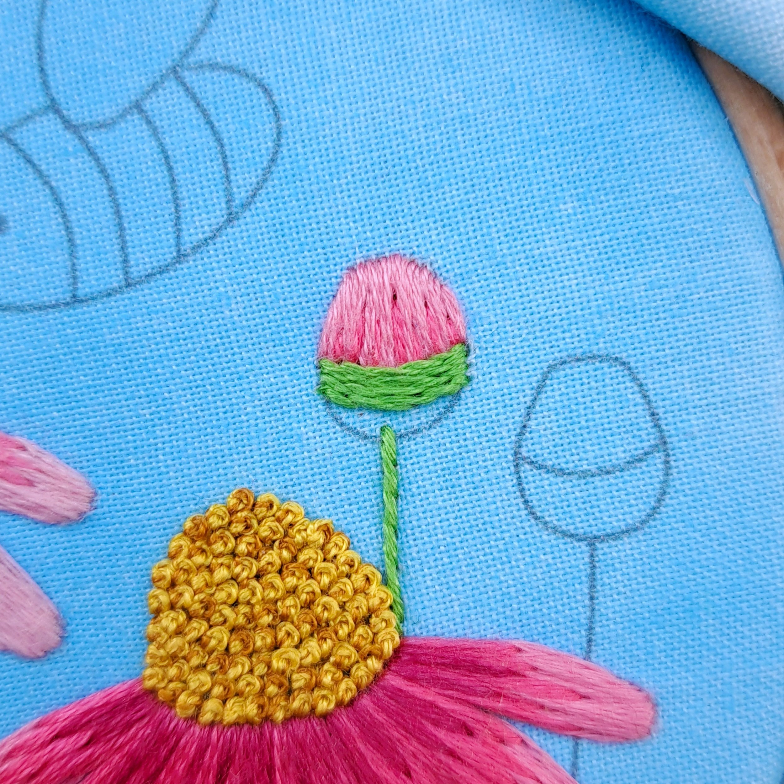 Close-up of partially stitched green Stem Stitches used to embroider the bottom part of a flower bud.