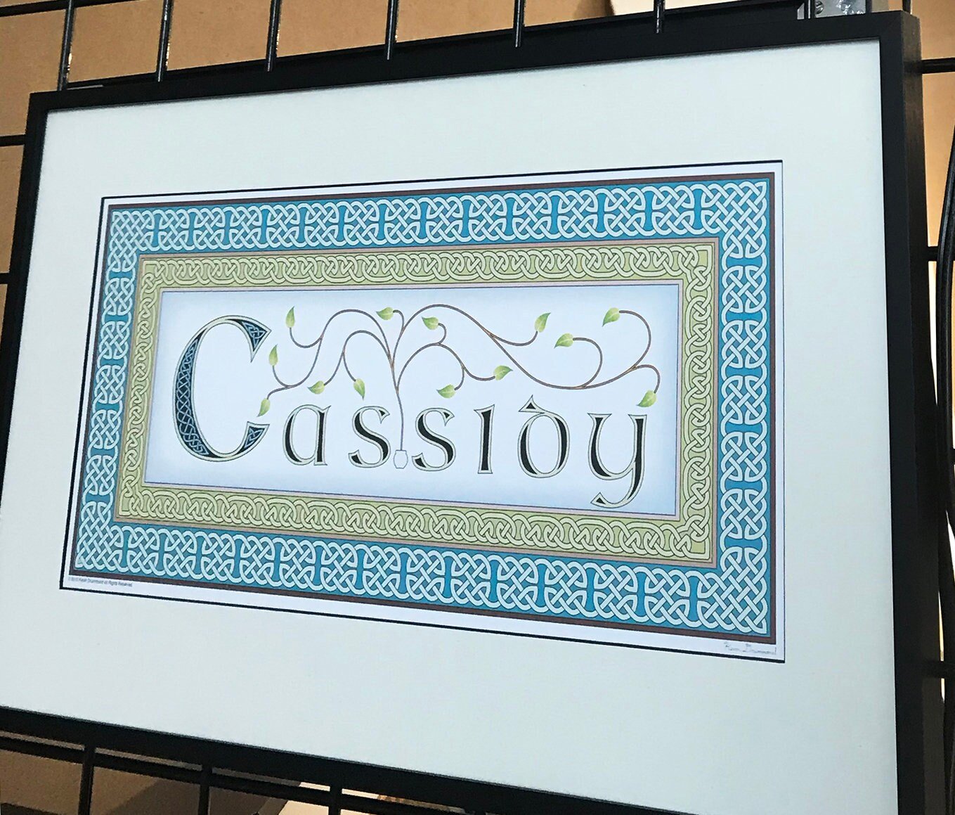 Irish surname Cassidy in teal and green, framed with white mat