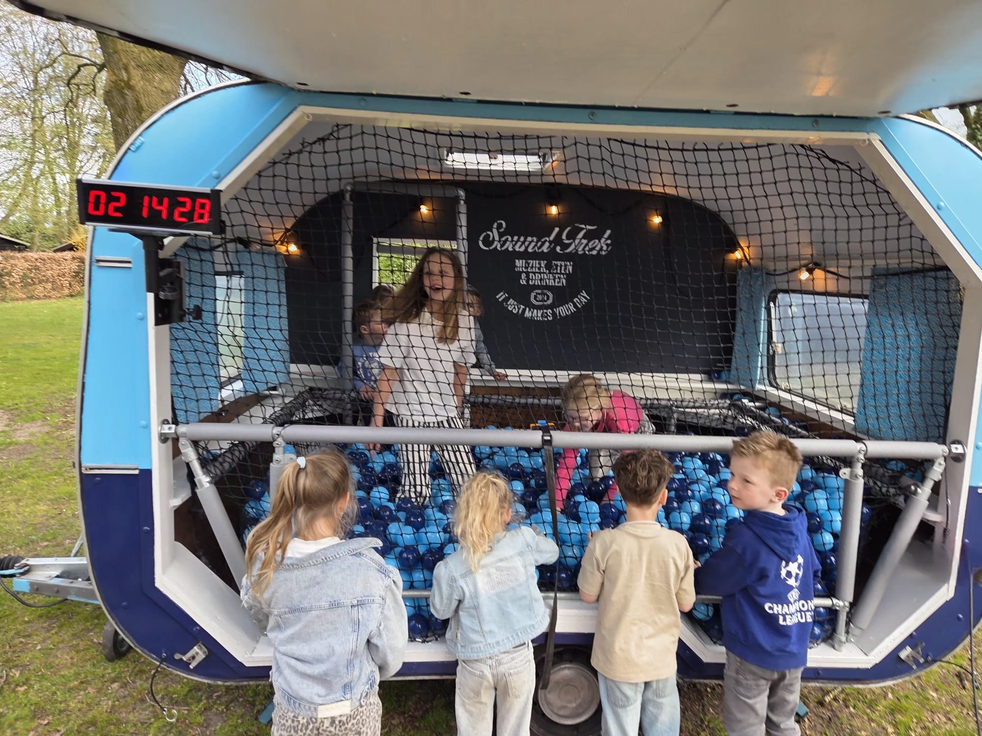 Kinderen spelen in een mobiele ballenbak in een caravan, een activiteit voor festivals, feesten en events