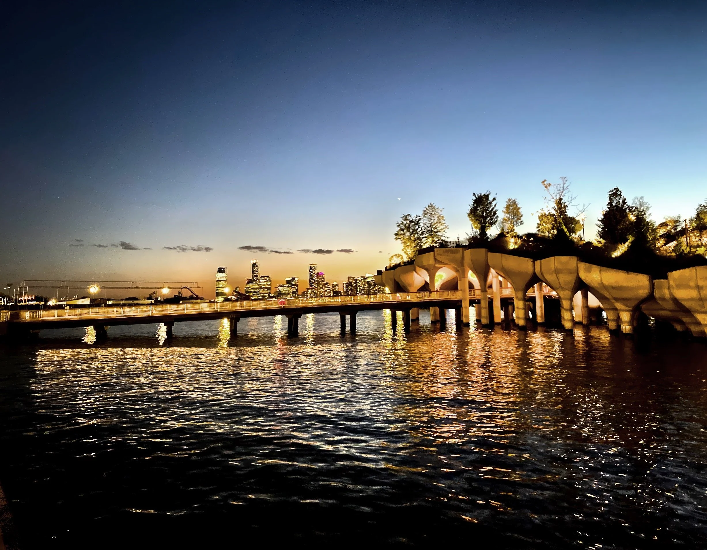  The lighted walkway entrance to Little Island as night takes over the sky 