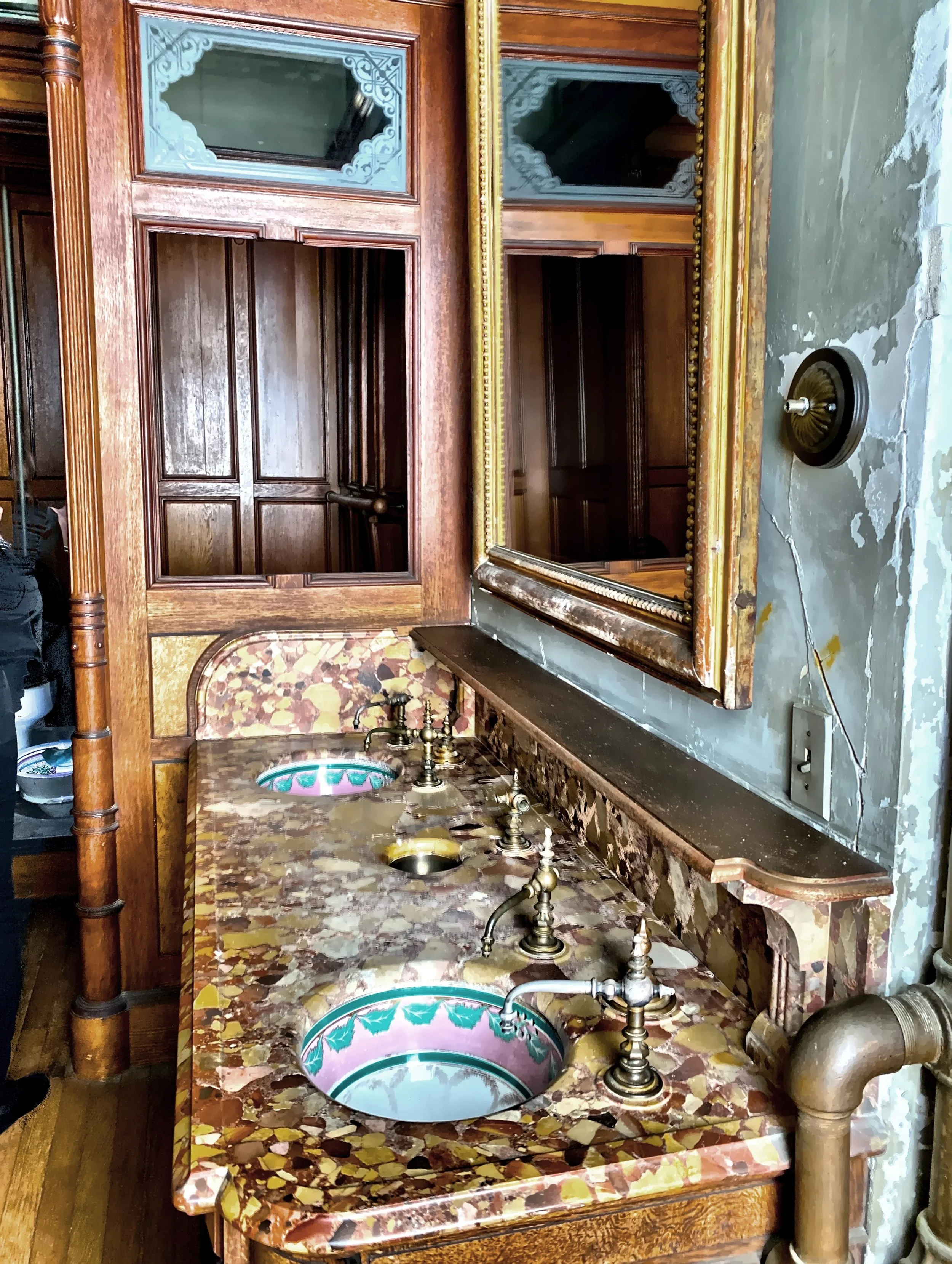  This is Mr. Lockwood’s adjoining bathroom, with double sink, water closet and tub designed by the Herter Brothers.  The double English ceramic sink basins are decorated in the same colors as the bedroom and are set in Italian Brescia marble. 