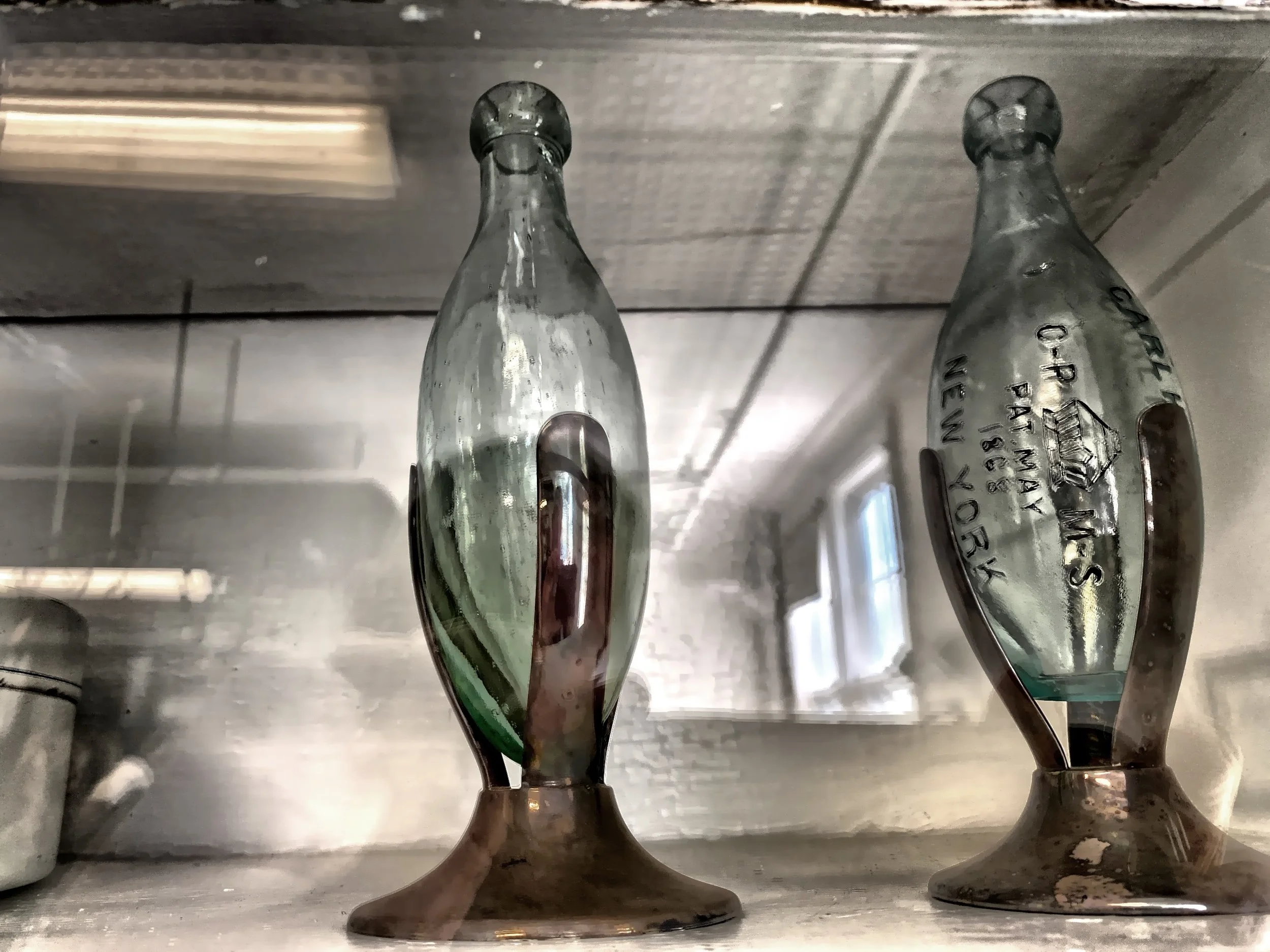  Here are a few torpedo bottles, in the their stands, in one of the cabinets in the prep area of the kitchen.  Torpedo bottles were used by the middle and upper class between 1870’s and 1910’s.  They were also known as Hamilton bottles, and they were