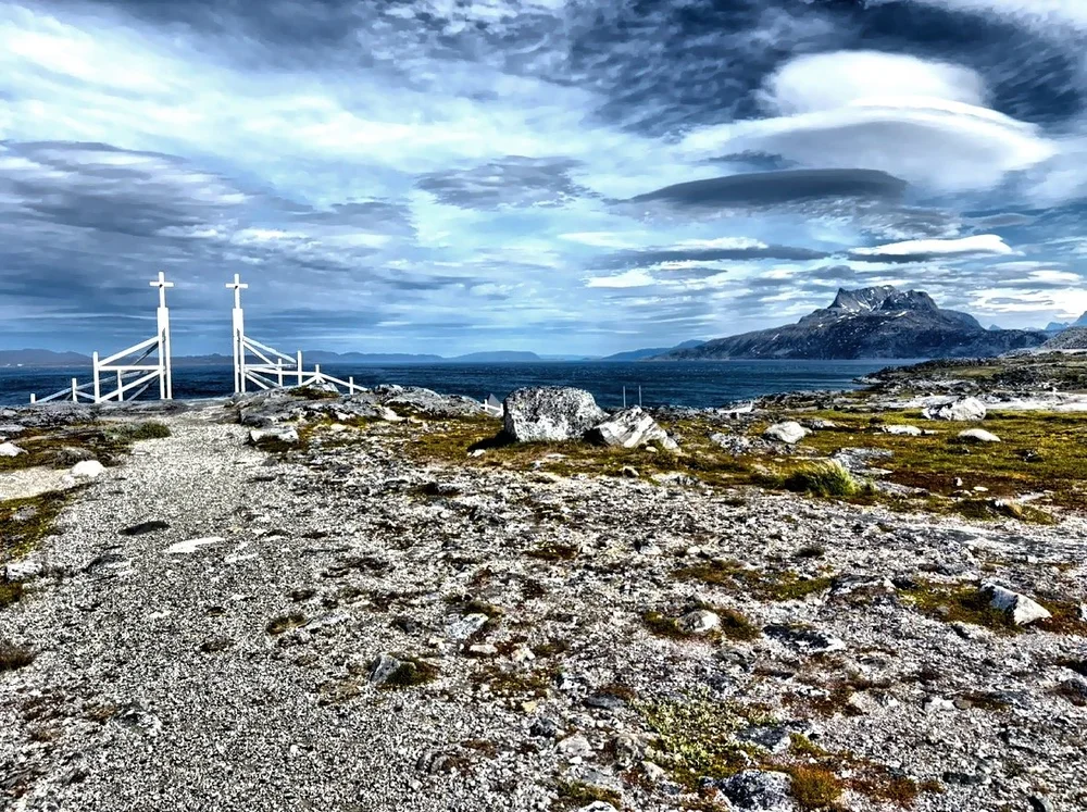  Just outside the heart of Nuuk lies one of the city’s most striking and peaceful places I’ve ever seen—Nuuk Cemetery.  Set against the dramatic backdrop of snow-dusted mountains and under a cloud streaked sky, the cemetery is both a place of rest an