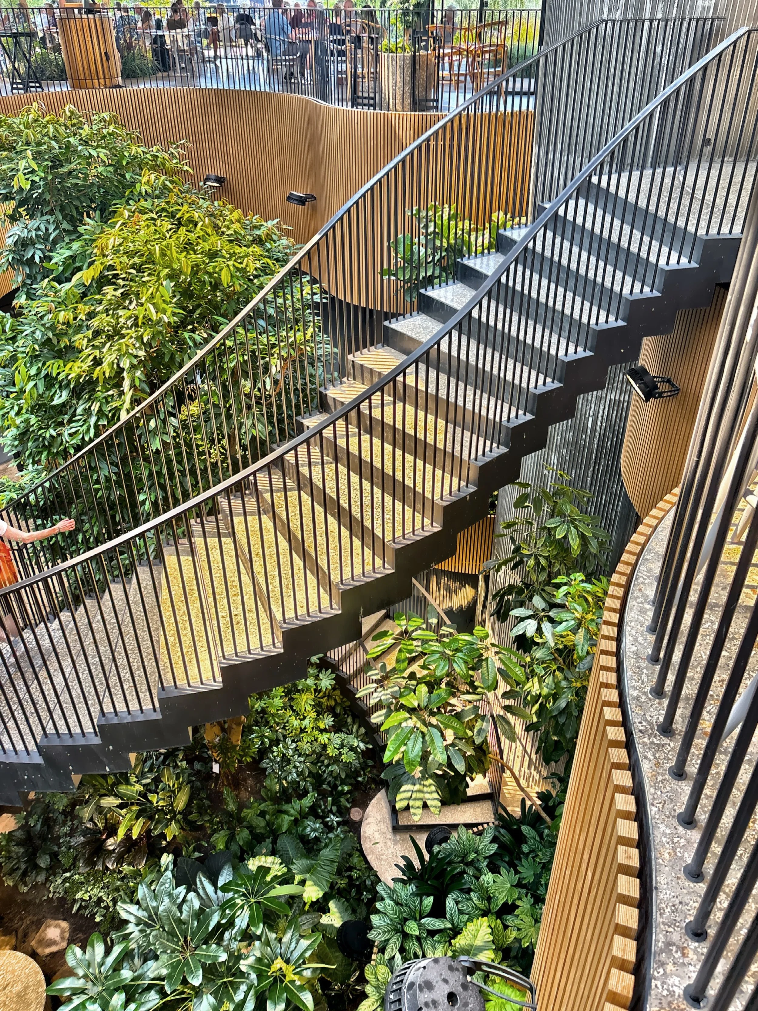  This spiral staircase through the indoor, underground garden is inside a greenhouse that serves as both a&nbsp;café&nbsp;and an entry point to the underground parking, integrating nature and utility in a seamless experience. 