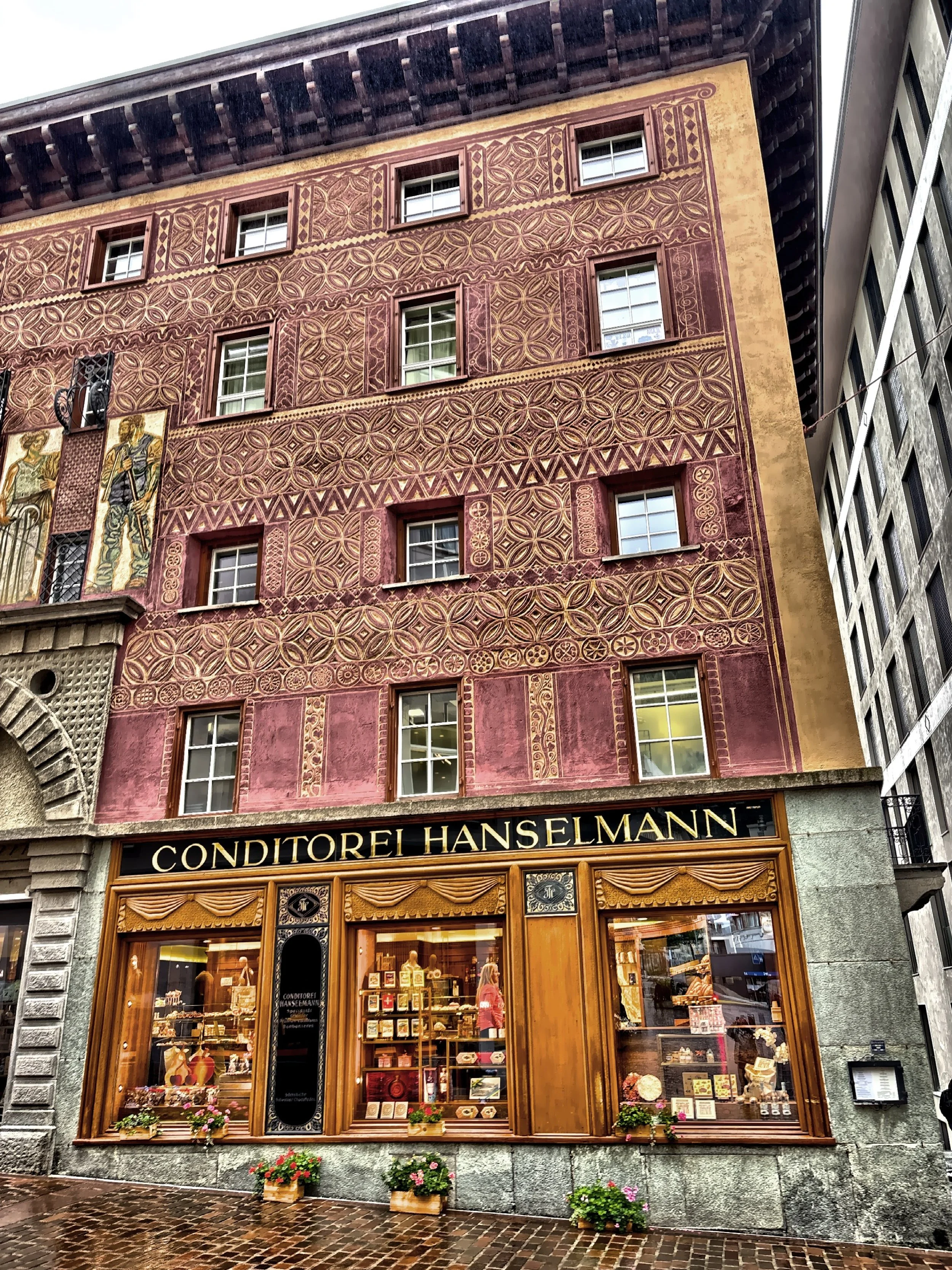  Opened in 1894, Conditorei Hanselmann, a historic cafe and bakery building has a notable of sgraffito on its facade.  This is a technique where layers of plaster are scratched away to create a design.   Opened in 1894, Conditorei Hanselmann is a his