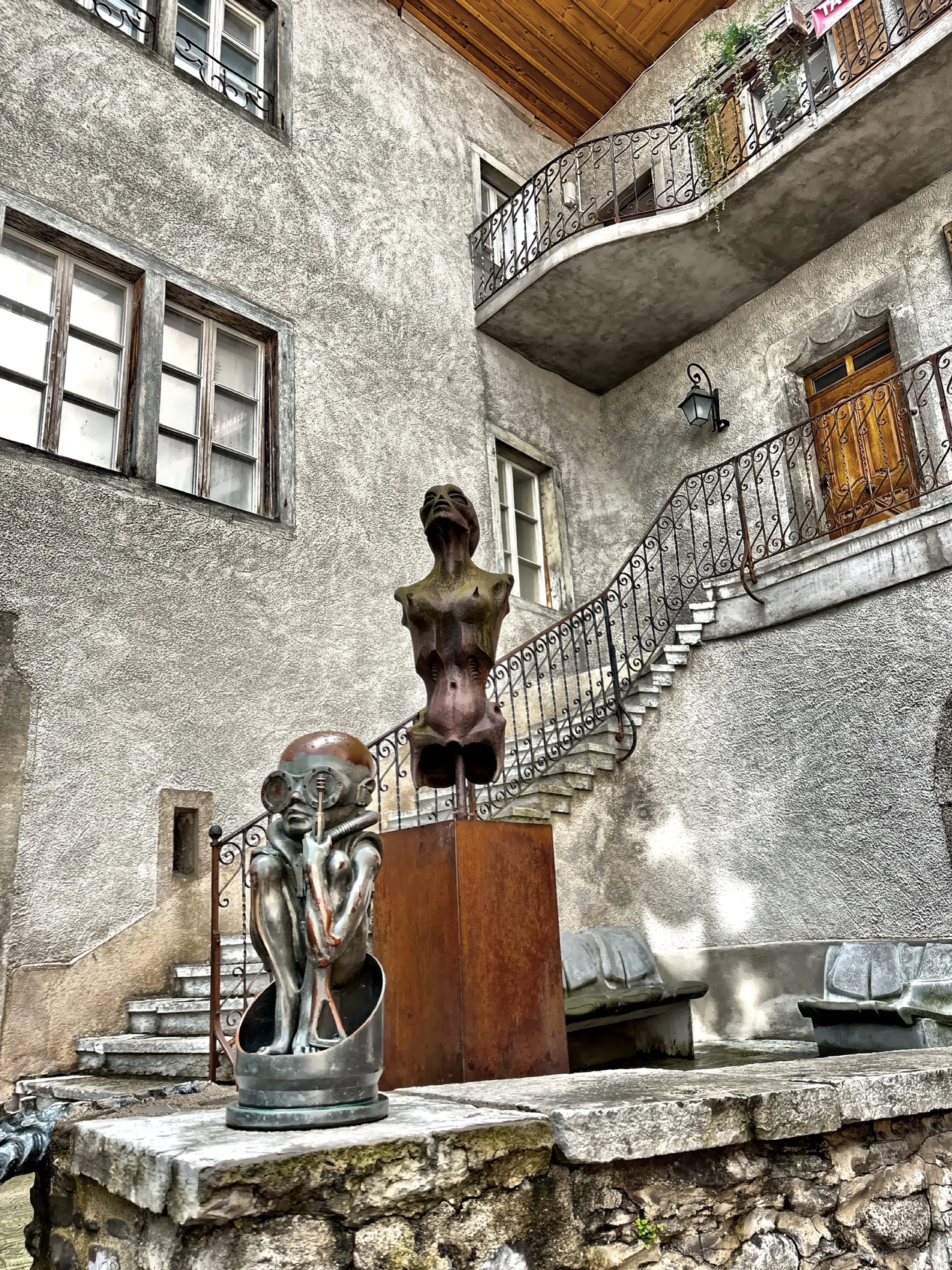  In the courtyard of the H.R. Giger Museum stand a series of striking sculptures by the Swiss artist, each one displaying his signature “biomechanical” style — a haunting fusion of organic forms and mechanical structures that feels at once alien, ele