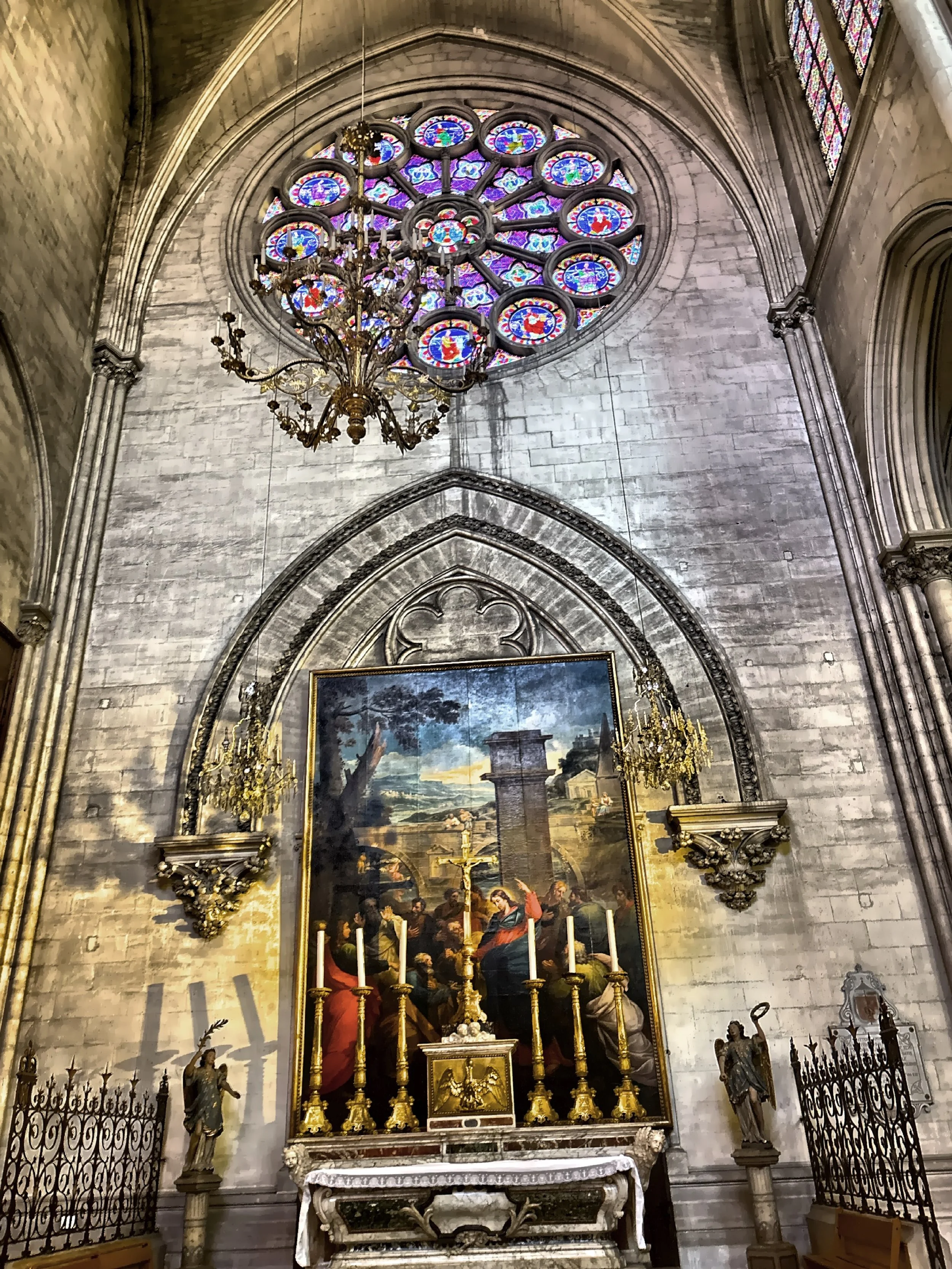  A large rose window and altarpiece painting below it. 