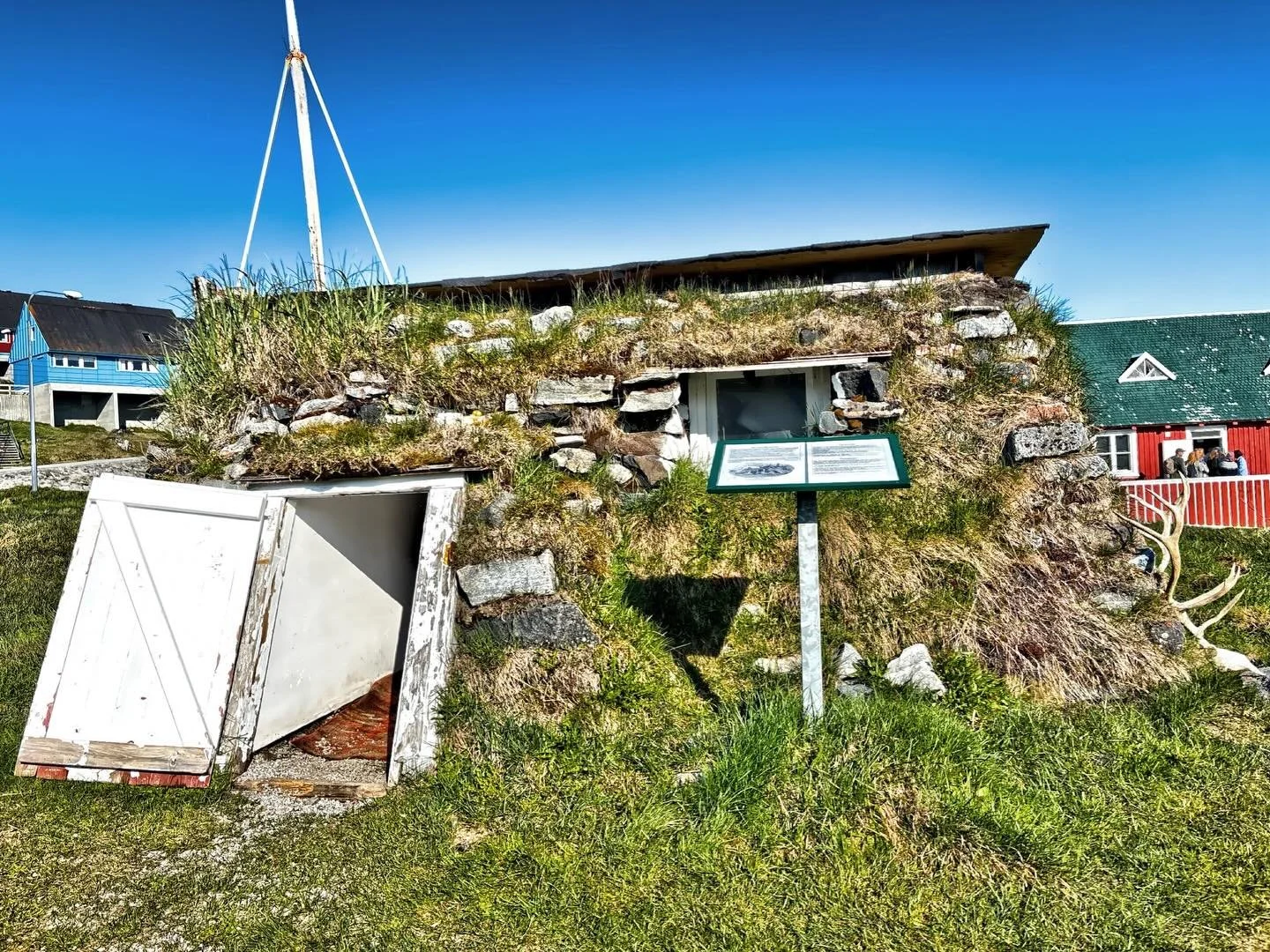 This is a reconstructed traditional turf house located in Paamiut, Greenland. These types of houses were historically used as winter accommodation in the region. The structure is built from stones and dirt, with a roof covered in sod and grass. Windo