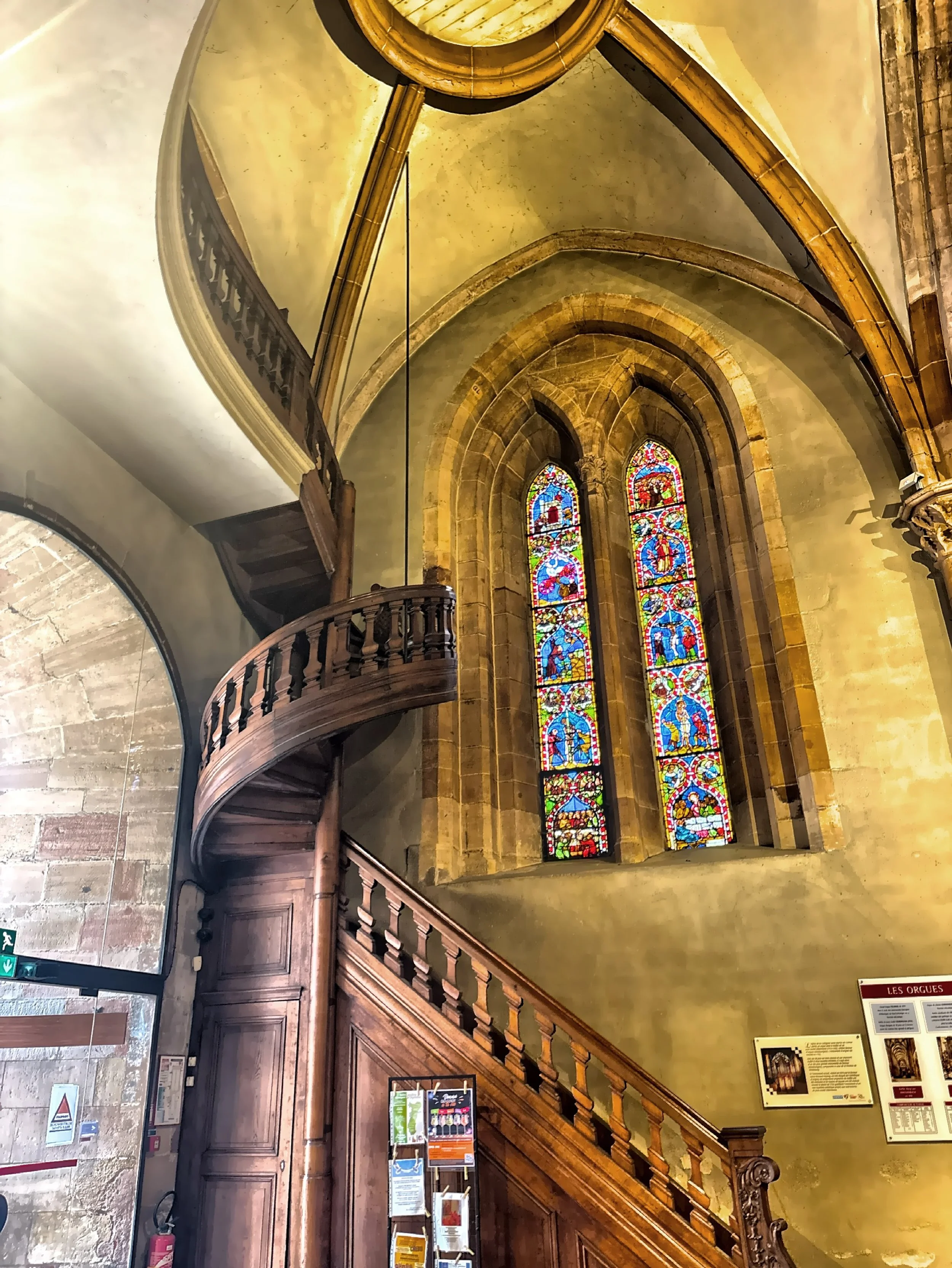  The interior features a prominent wooden spiral staircase along with vibrant stained glass windows. 