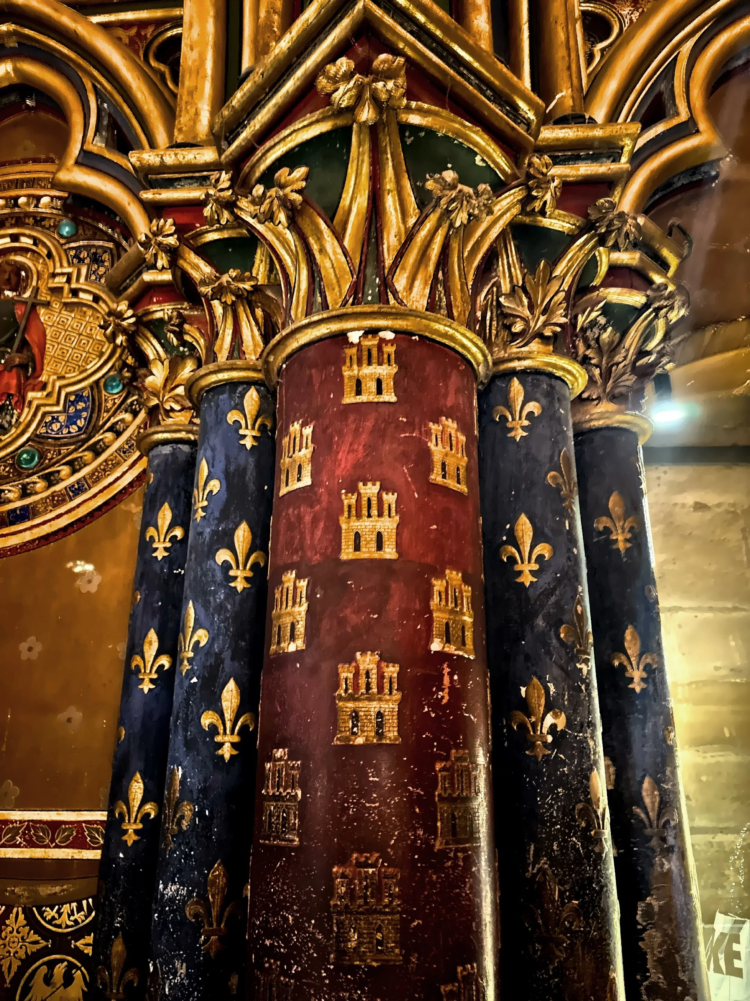 The columns feature intricate gold, red and blue painting with repeated gold castle motif. 
