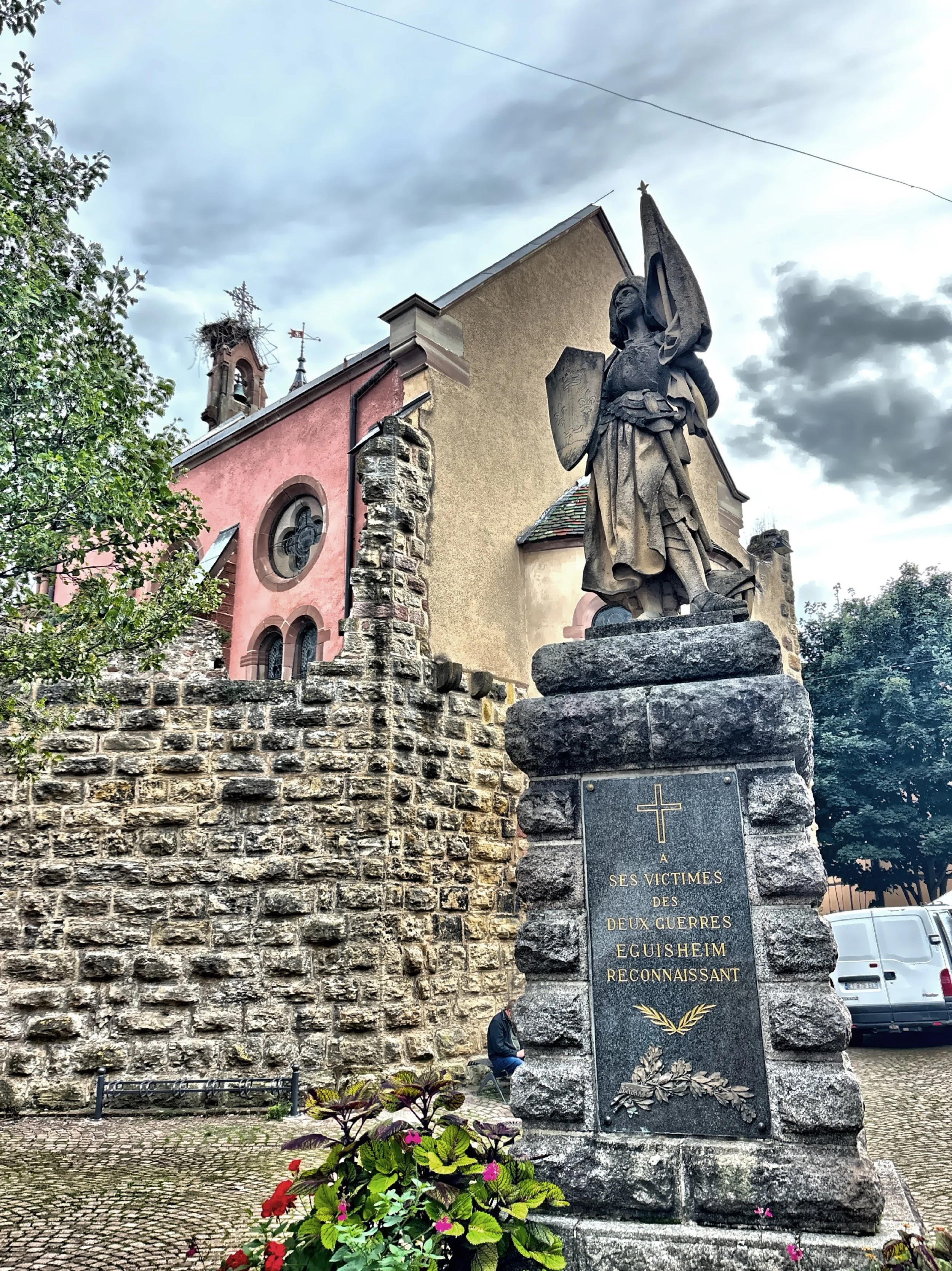  An angel crowns the town’s war memorial, commemorating 49 residents who lost their lives in the First and Second World Wars, with a stork’s nest visible on nearby rooftops in the background. 