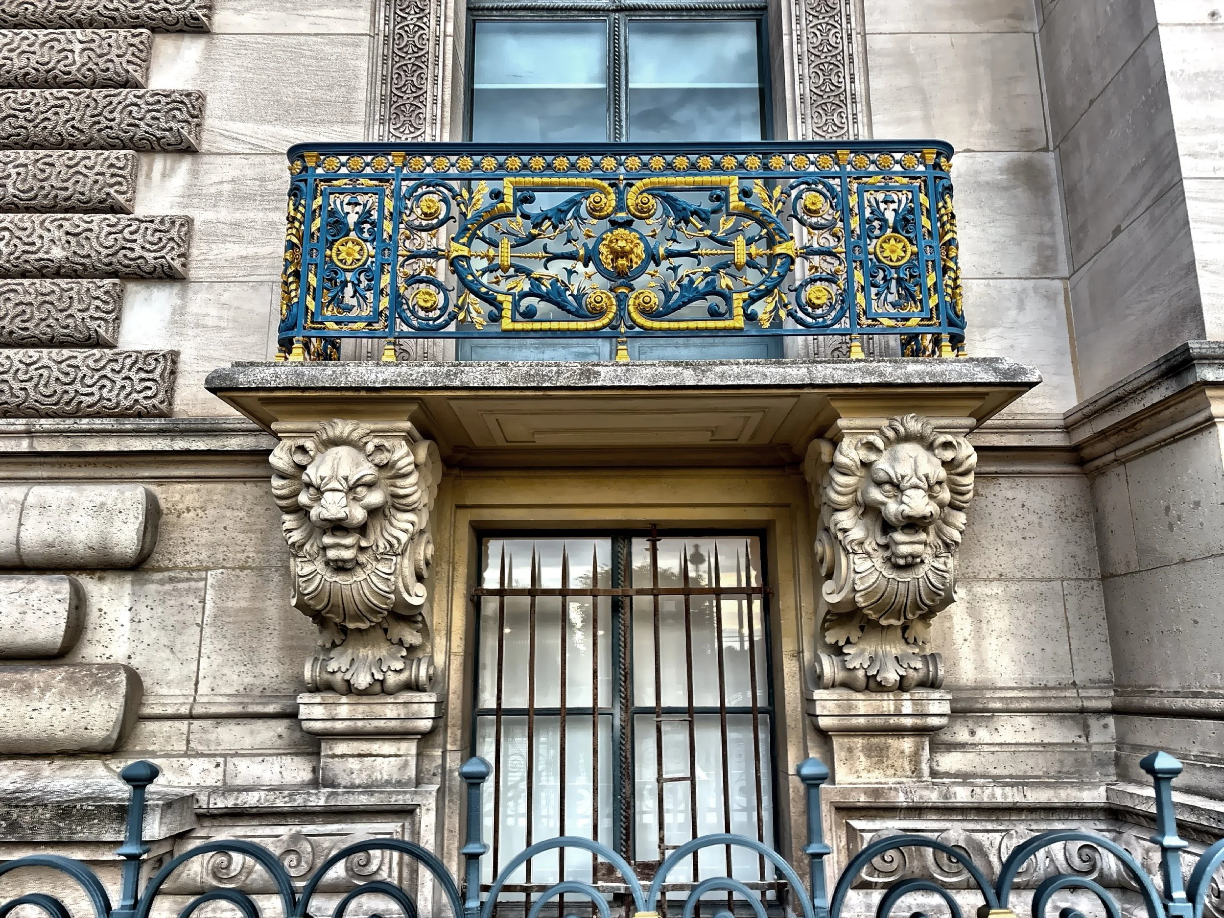  An ornate balcony with lion head sculptures in the typical Parisian Second Empire style. 