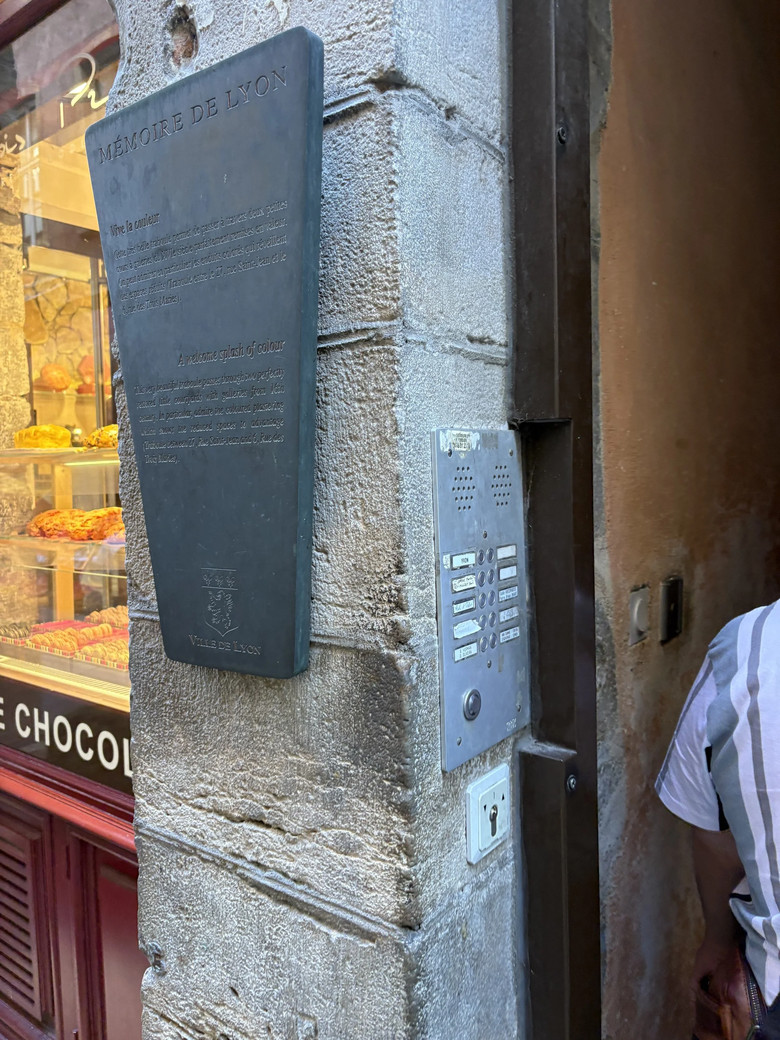  The plaques mark the secret passages known as traboules. There are about 300 of these winding alleys that pass through buildings and courtyards offering shortcuts.  They are often masked as residential of commercial entrances.  In the past they were