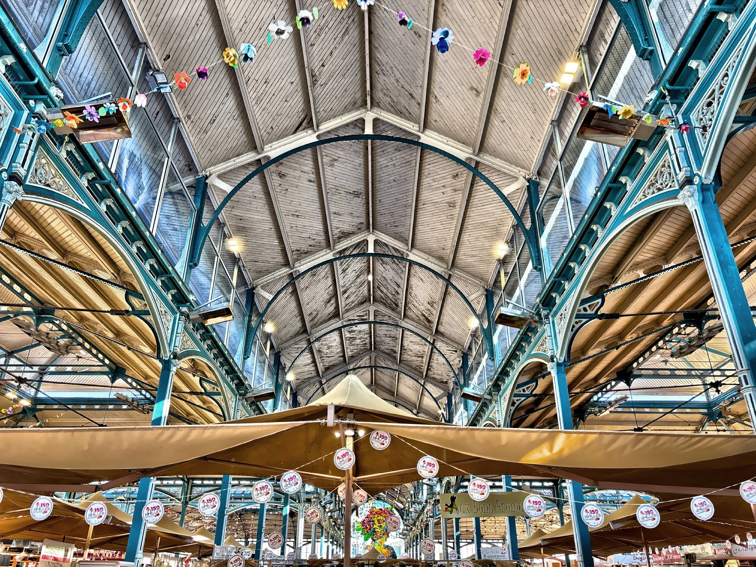  The view inside the historic Les Halles de Dijon, a vibrant covered market built between 1873 and 1875. Its striking iron framework—designed by Gustave Eiffel—adds an industrial elegance to the space, where rows of stalls brim with fresh produce, re
