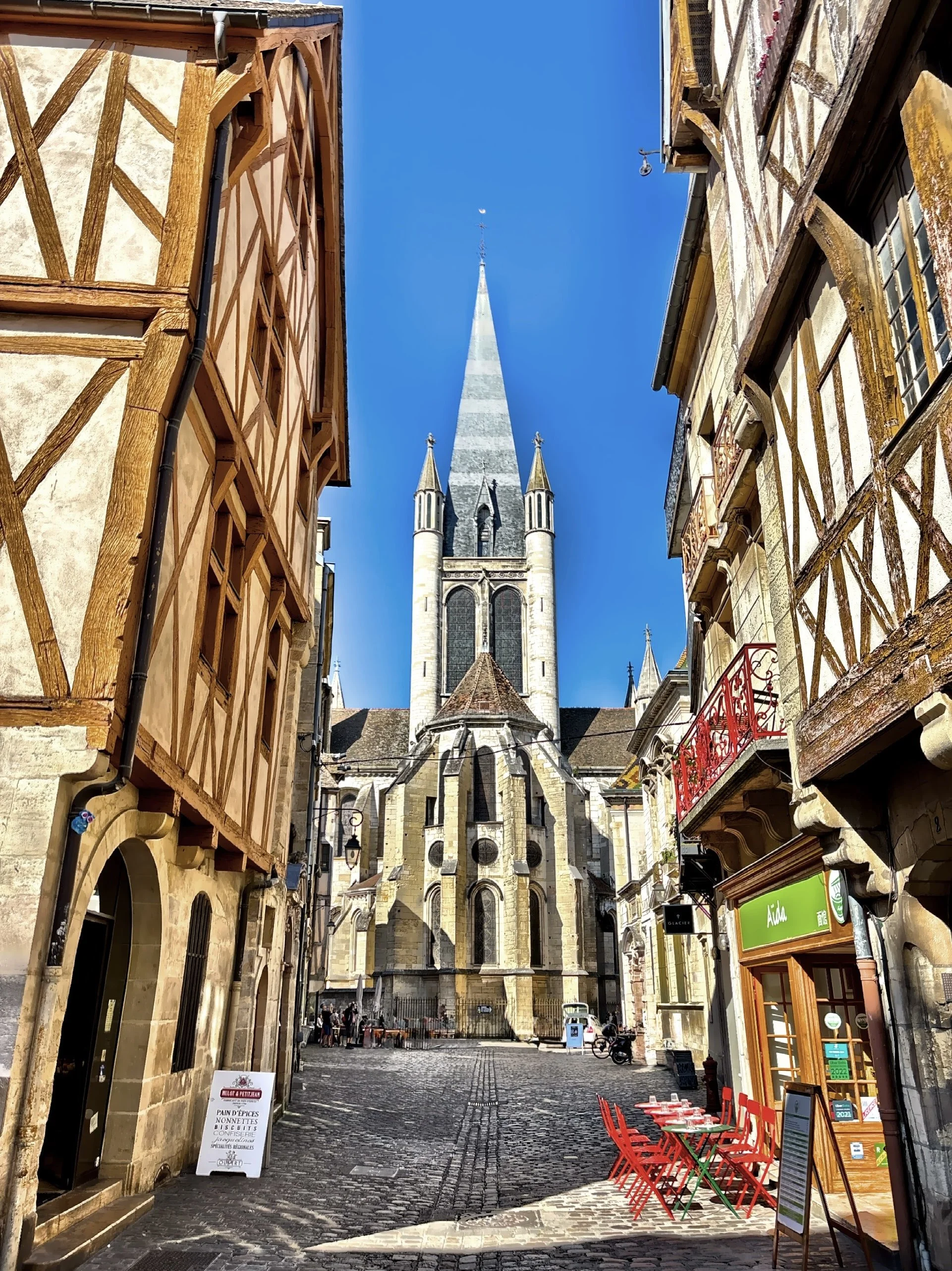  Notre Dame of Dijon stands at the end of a street of half-timbered buildings. 