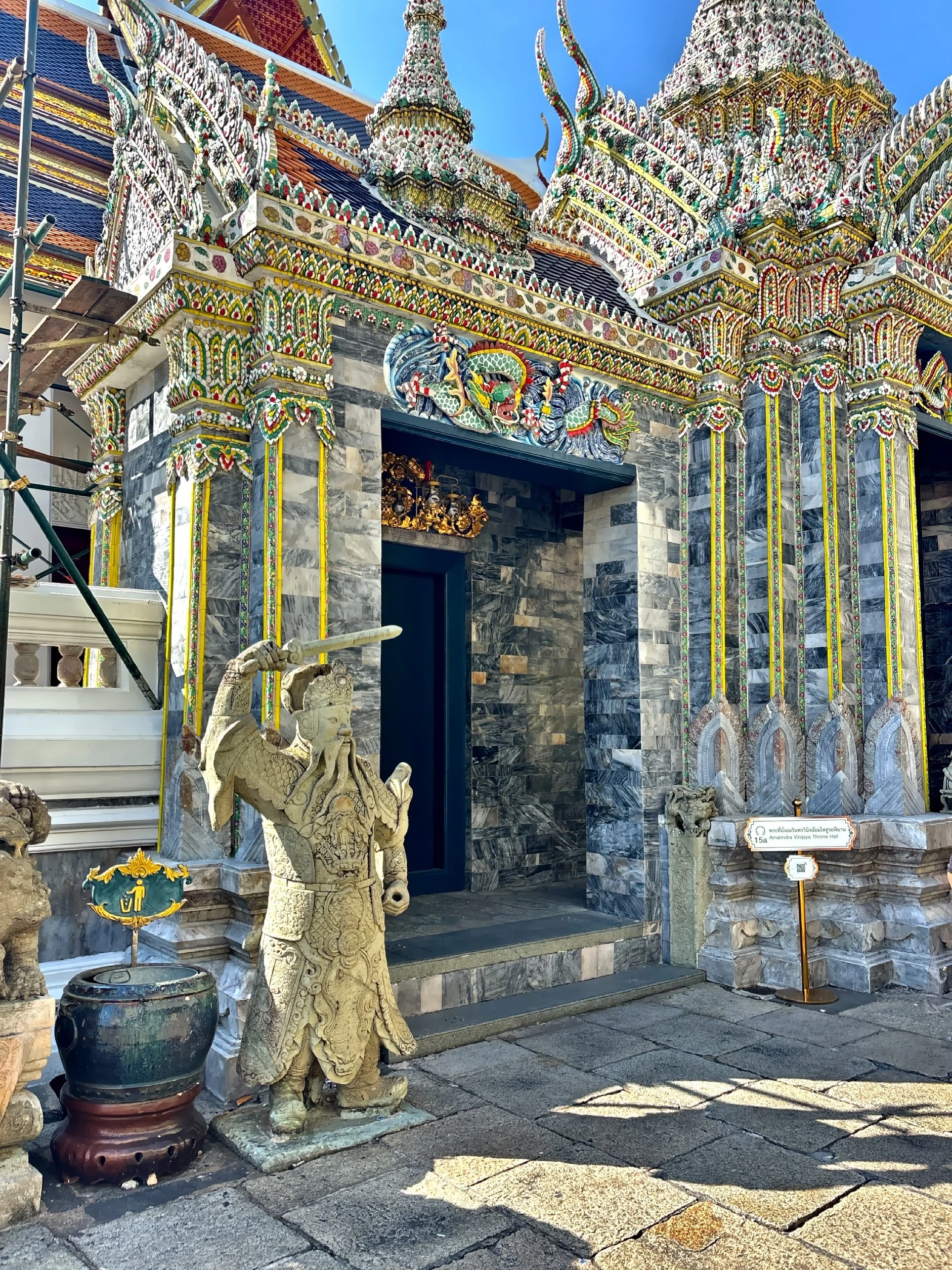  The intricate architecture of Wat Kaew (Temple of the Emerald Buddha) guarded by the warrior statue. 
