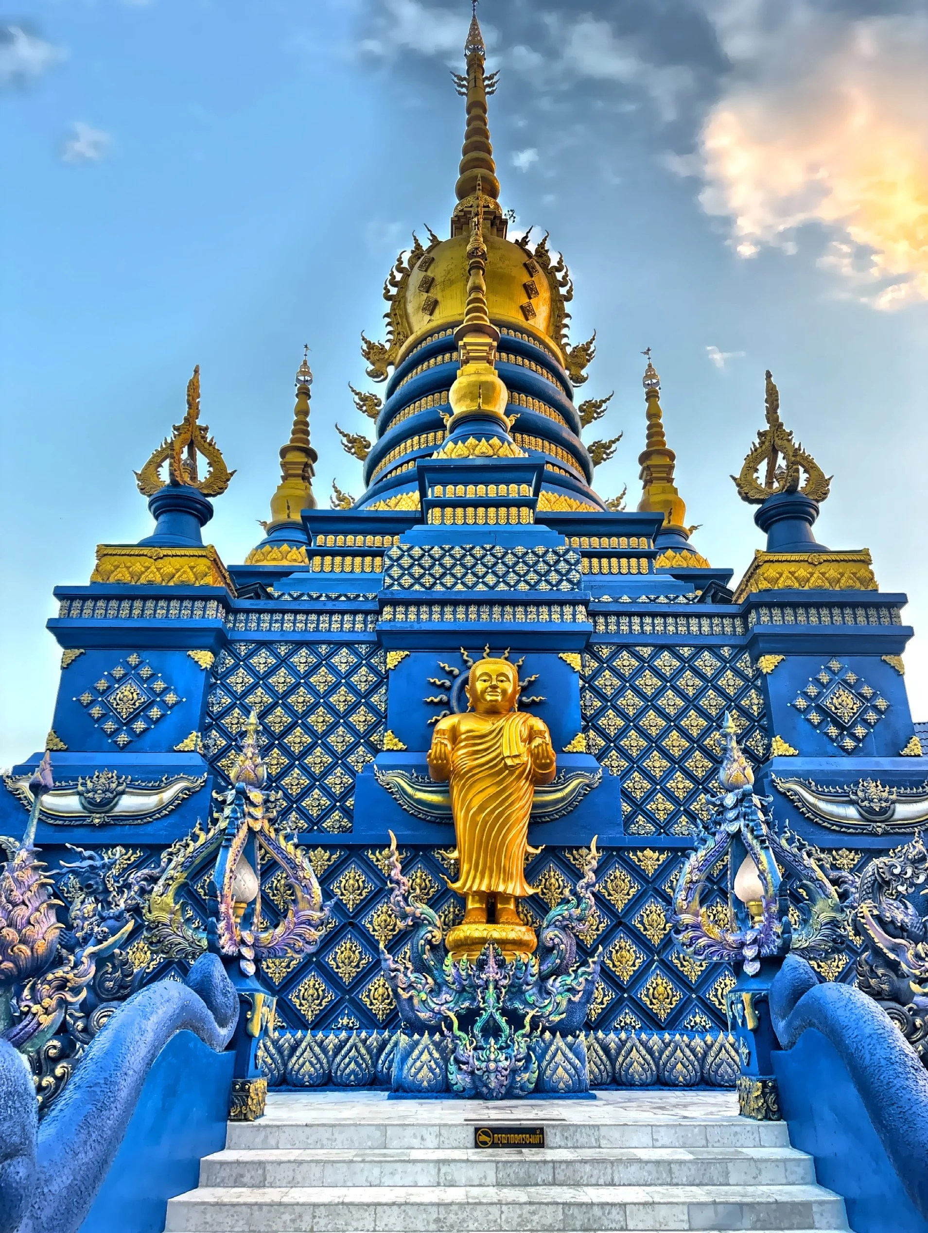  The temple grounds feature a prominent standing golden Buddha statue. 