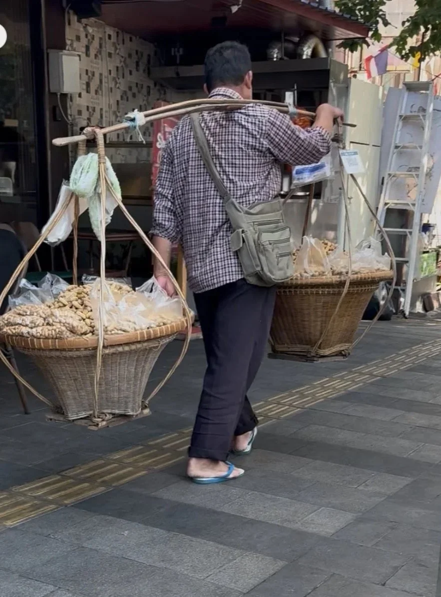  A street vendor carrying goods using a traditional shoulder pole. 