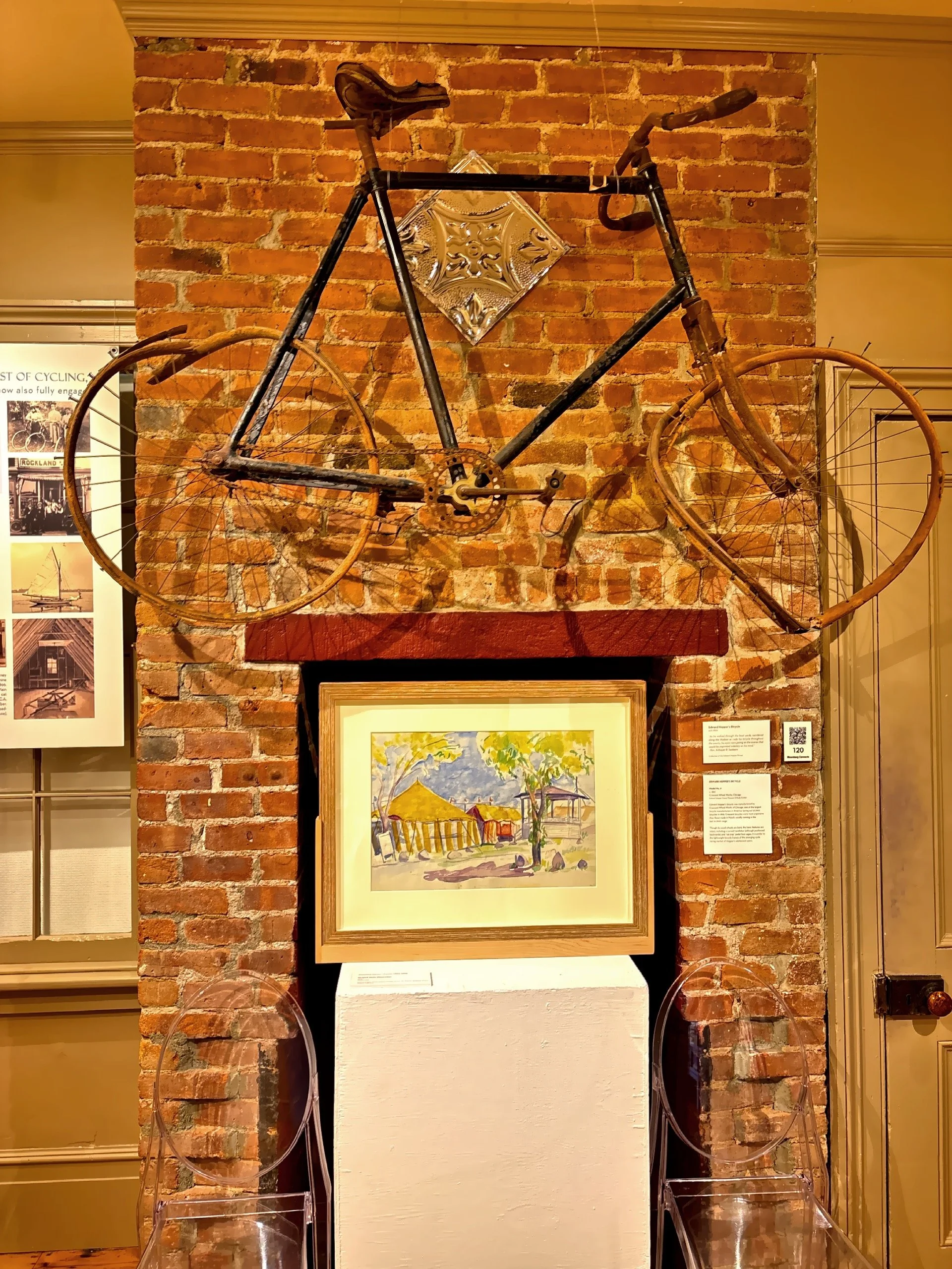  Hopper’s bicycle above a watercolor  painting titled ‘Striped Tents. Gloucester’ painted in 1928 by Josephine Nivison Hopper. 