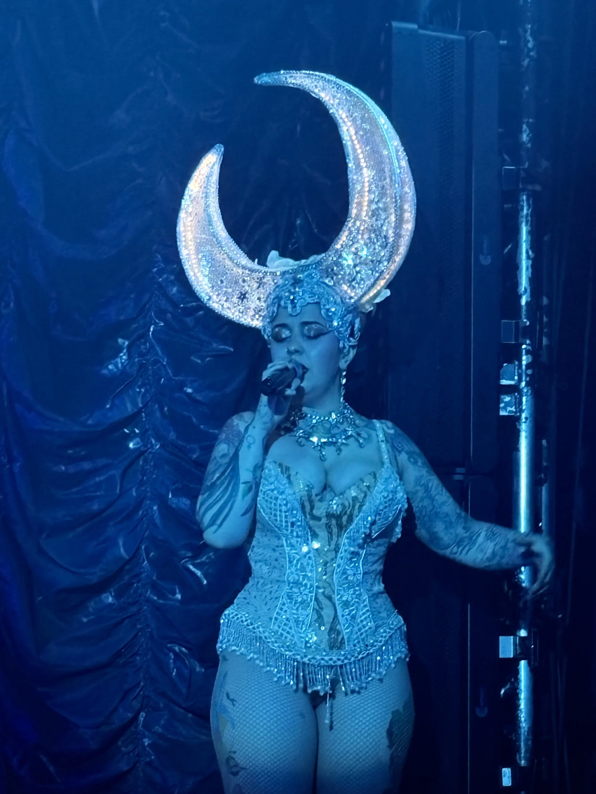  One minute there’s a torch singer delivering a heartbreak ballad under a single spotlight; the next, an aerialist is spinning upside down over the stage. 