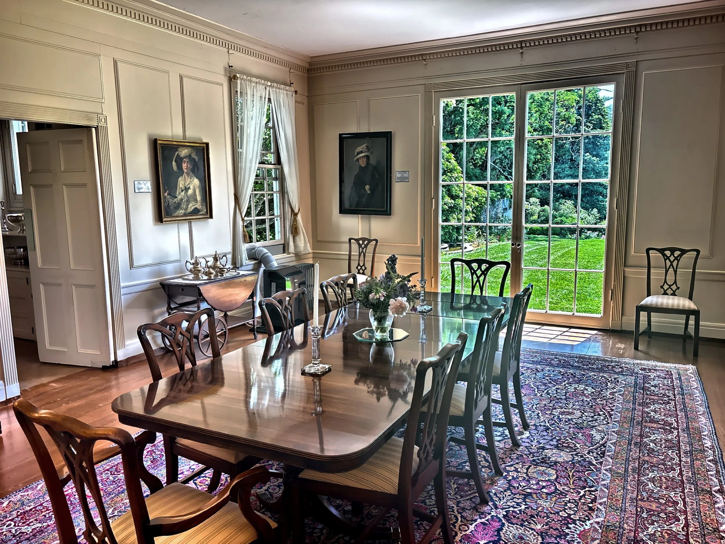  The formal dining room with paneled walls, period art and a large polished dining table. 