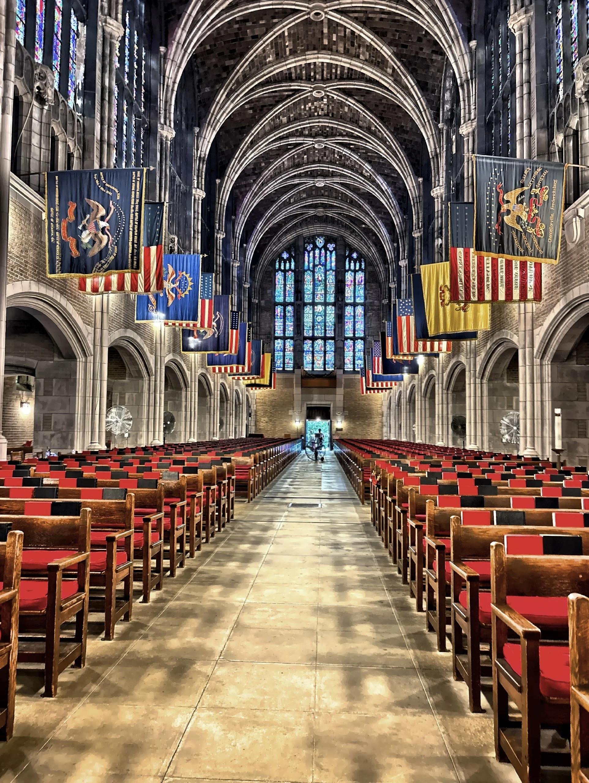  High vaulted ceilings, colorful stained-glass windows, and rows of flags hanging along the nave. 