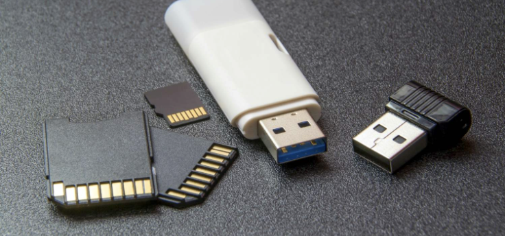 Two USB flash drives, a microSD card, and a microSD card adapter on a dark surface.