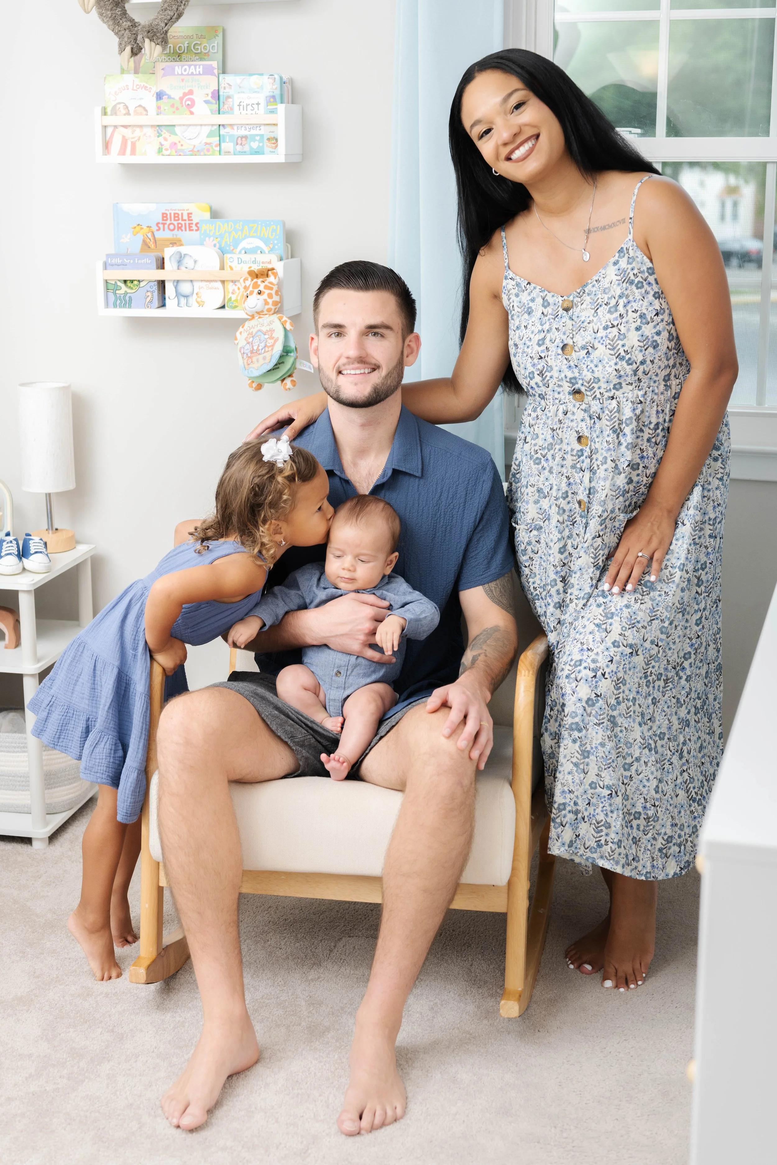 A family sharing a tender moment in a bright, airy nursery during a relaxed, home lifestyle newborn photography session in Maryland.