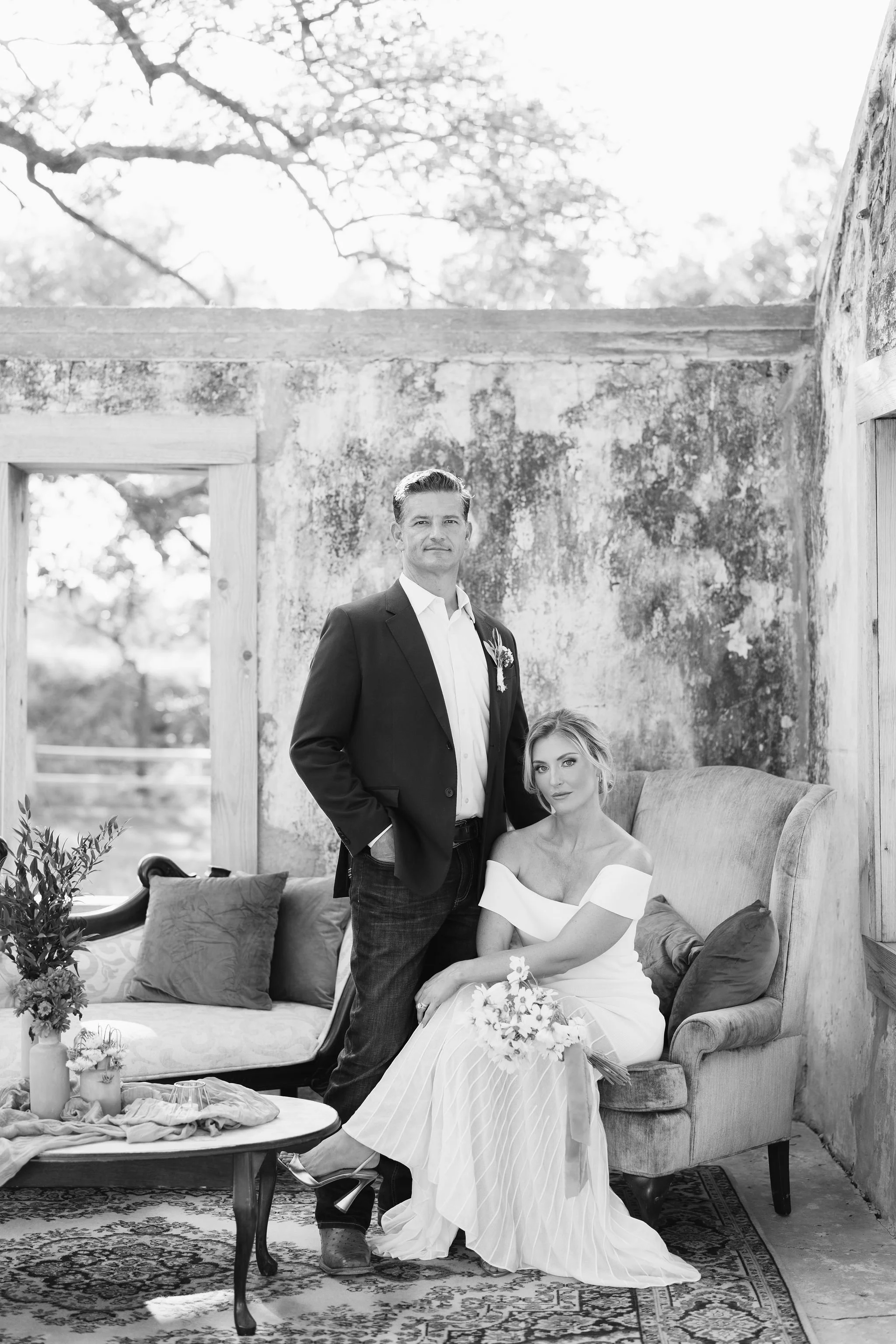 Luxury wedding photography in Fort Worth Texas showing black and white image of groom standing over the bride in a outdoor stonehouse