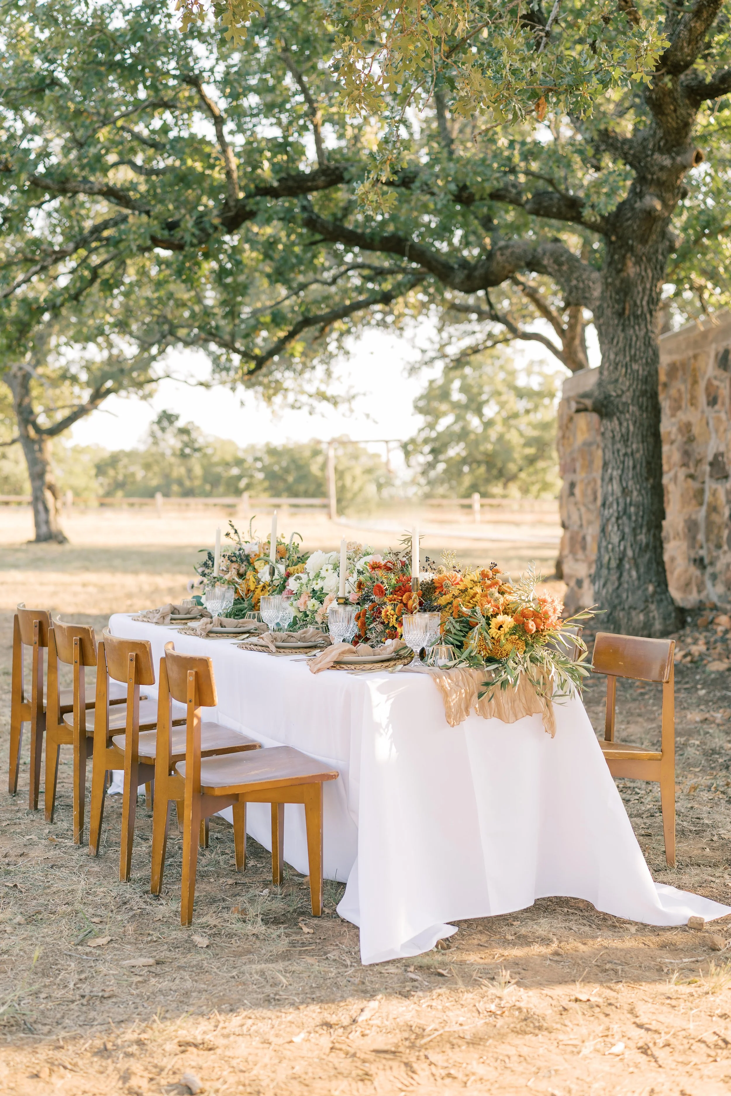 Luxury wedding outdoor tablescape with warm color floral and candle arrangements