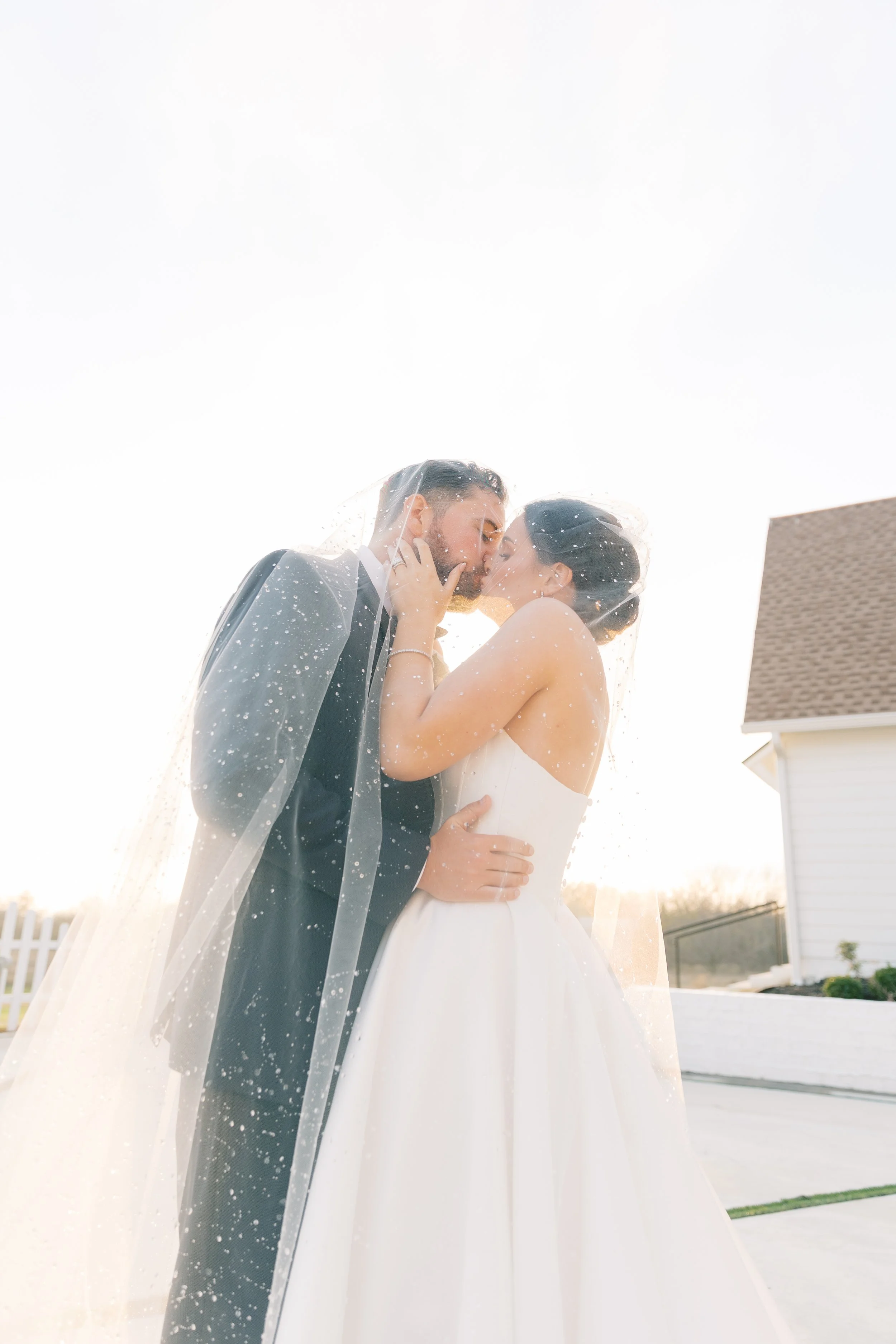 Bride and groom kiss under long wedding veil
