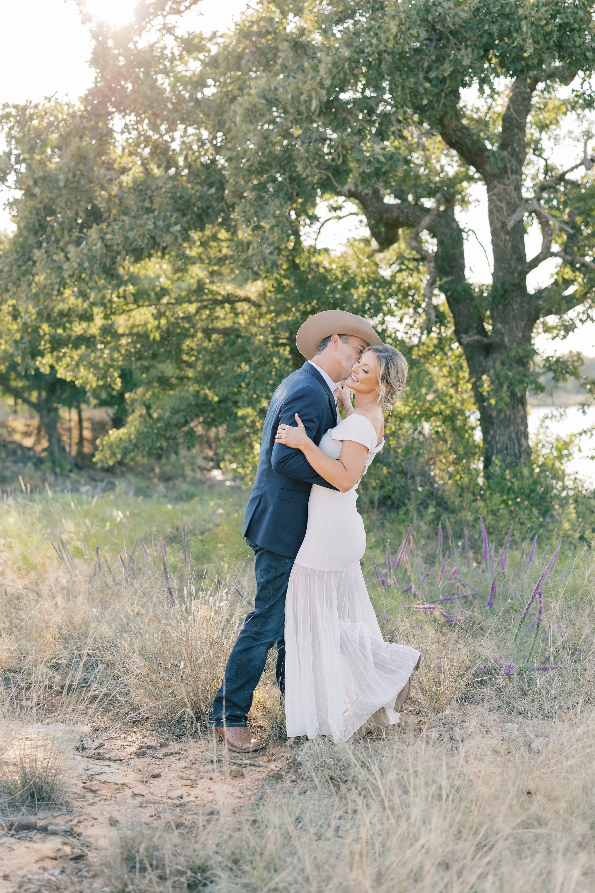 Cowboy hat groom hugs bride during golden hour