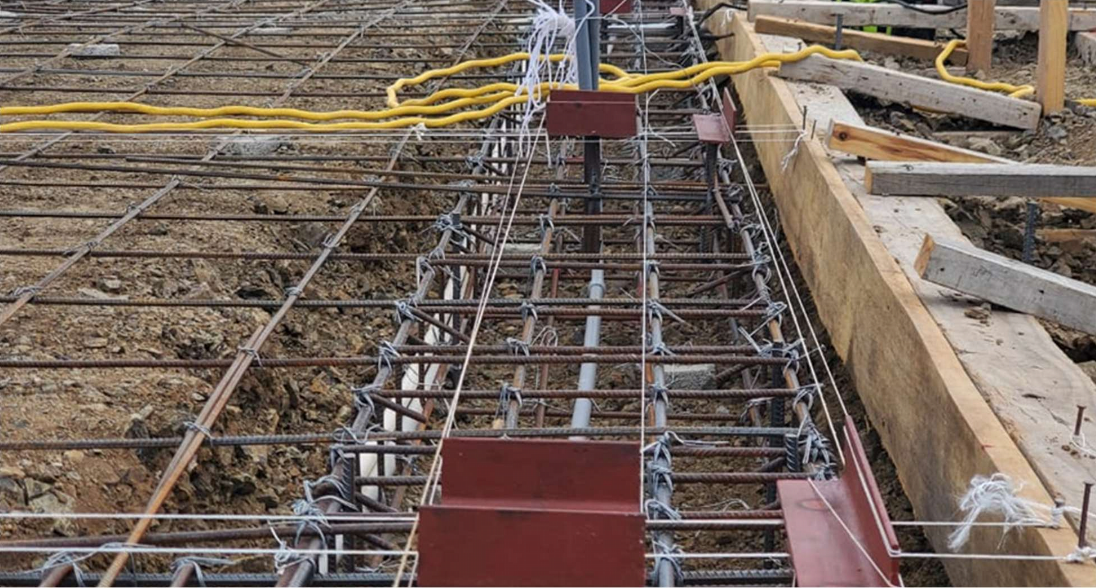 Rebar, conduits and plumbing was installed prior to concrete pour. The red metal pieces are for anchoring the 6x6 columns into the foundation.