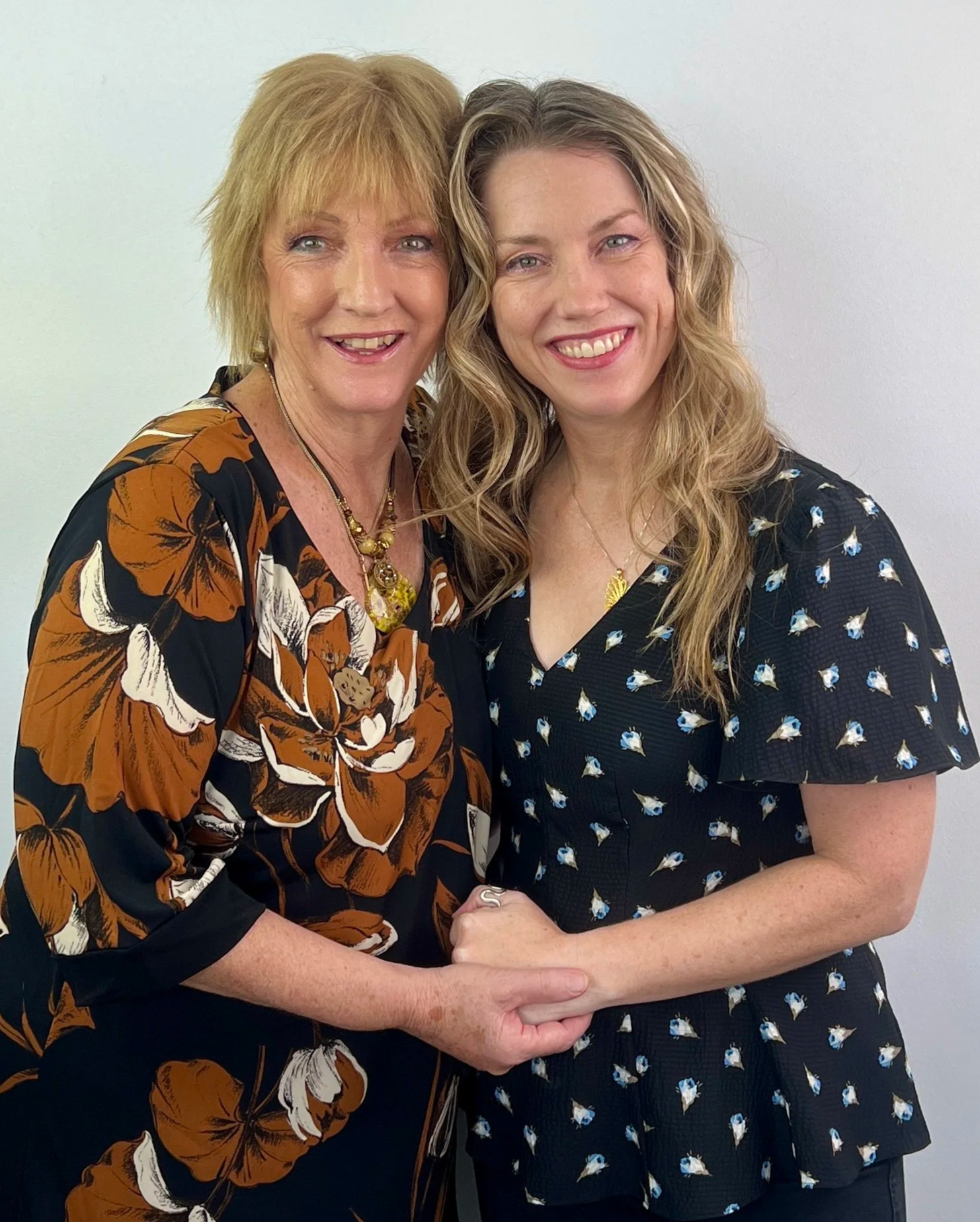 Karen with her artist mum, Jennie Bell, are facing the camera in an embrace, to welcome visitors to their mother-daughter art exhibition, "Let Colour Speak"