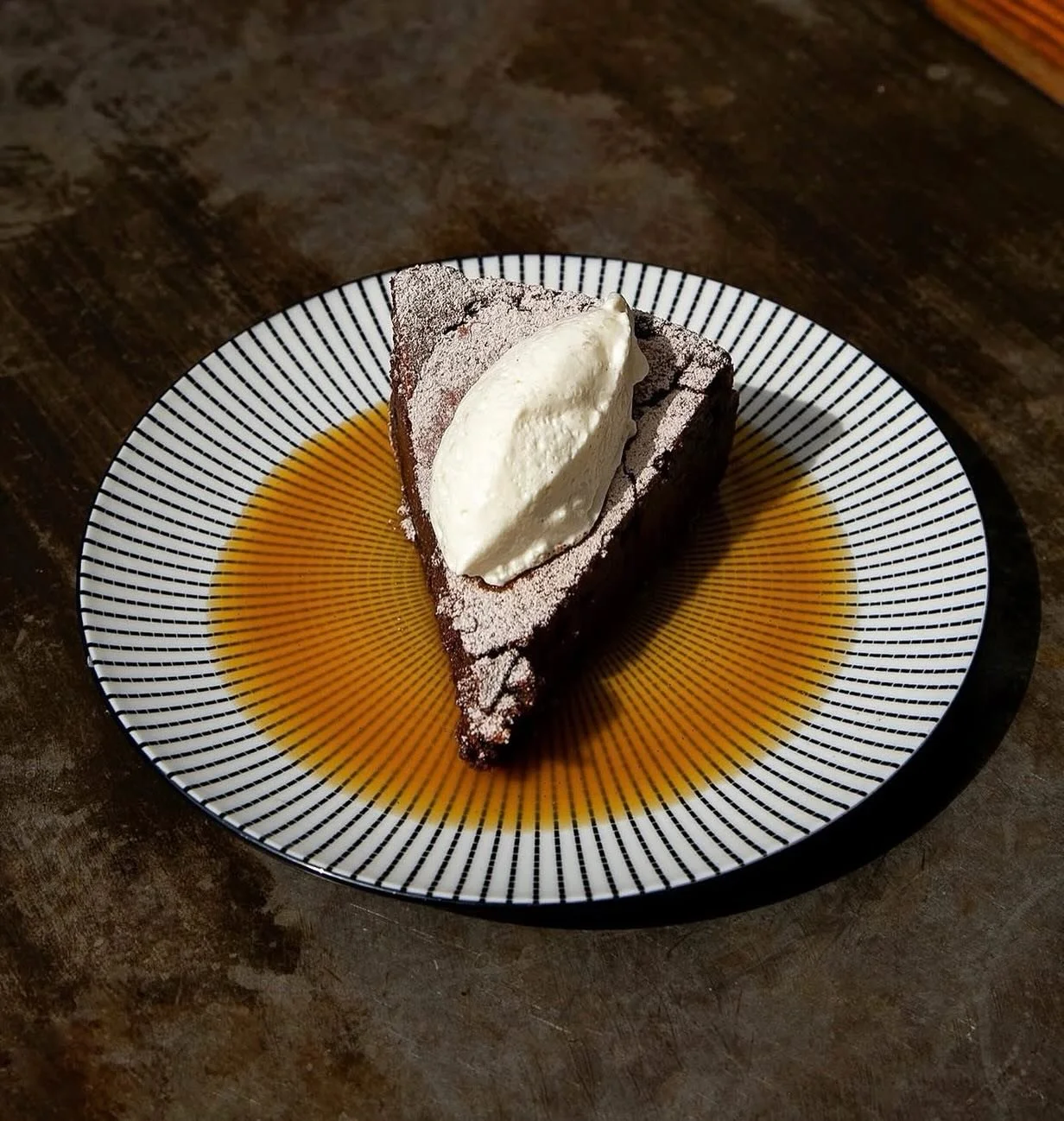 Serving main character energy: a decadent chocolate torte layered with espresso caramel, topped with whipped cream, and dusted with espresso powdered sugar. Gluten-free by coincidence, indulgent by design. 🤎☕✨ Come hang out tonight for our delicious