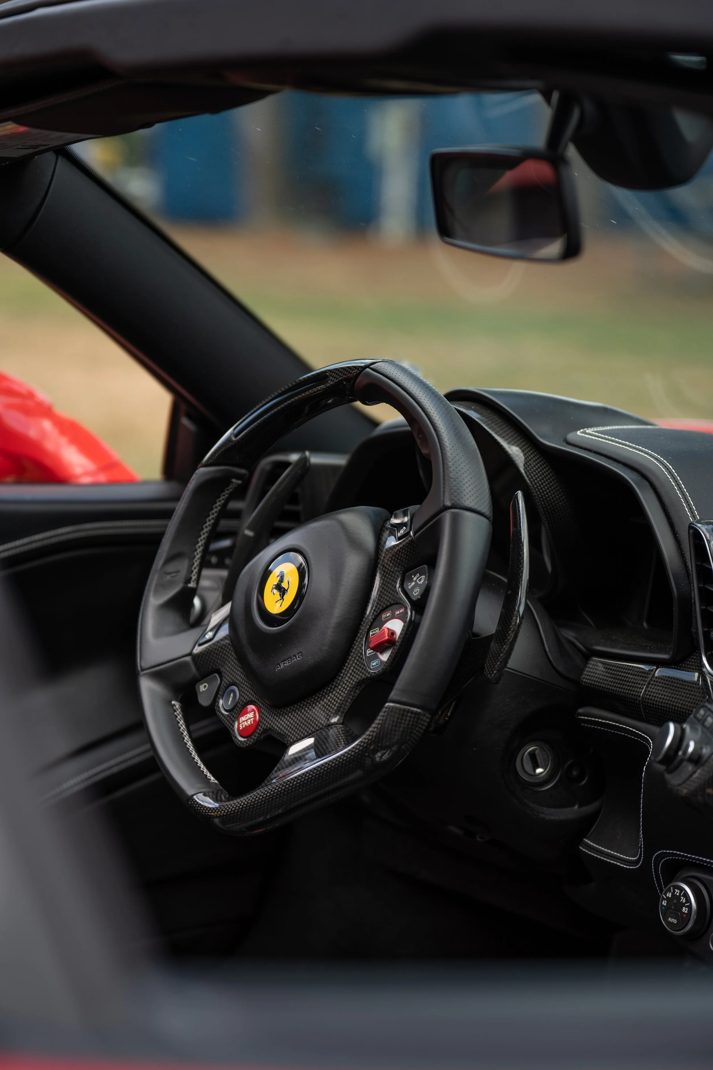 Interior of a race car with a steering wheel bearing the Ferrari logo, advanced controls, and a sleek dashboard.