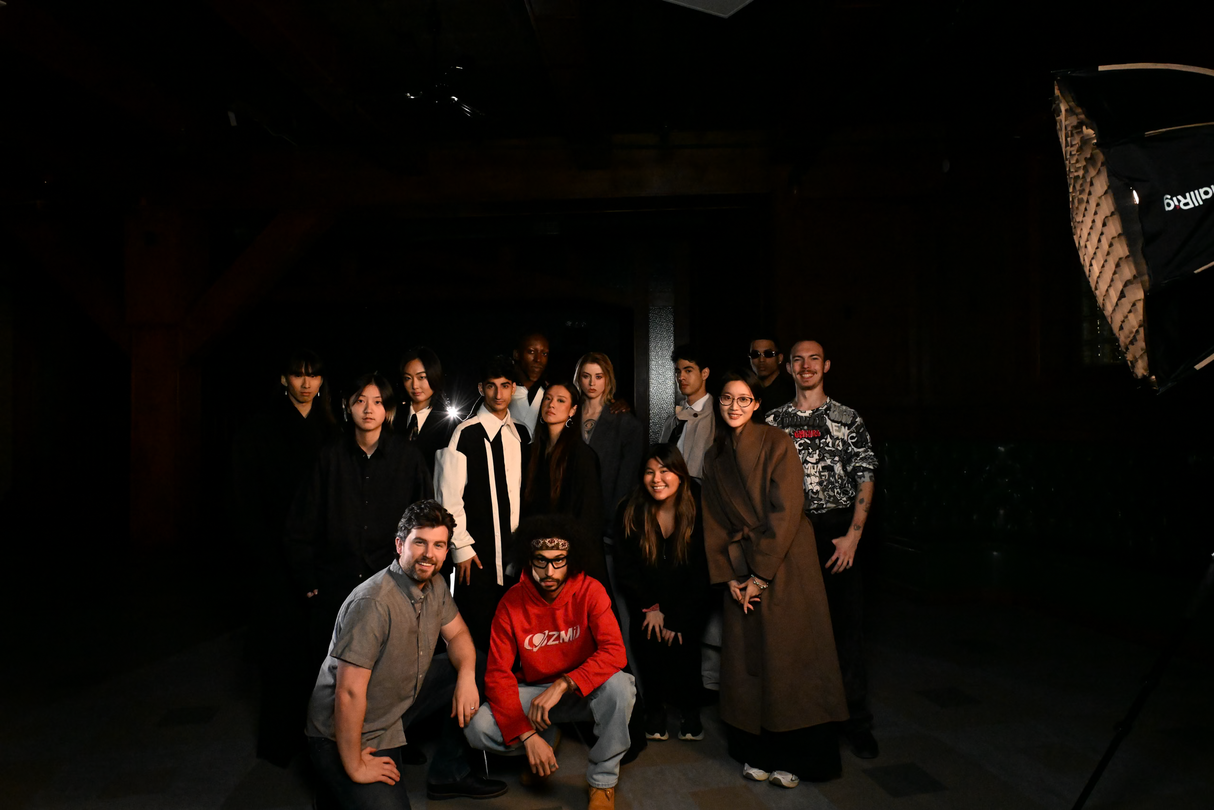 Group of diverse people posing for a photo indoors with dark lighting.