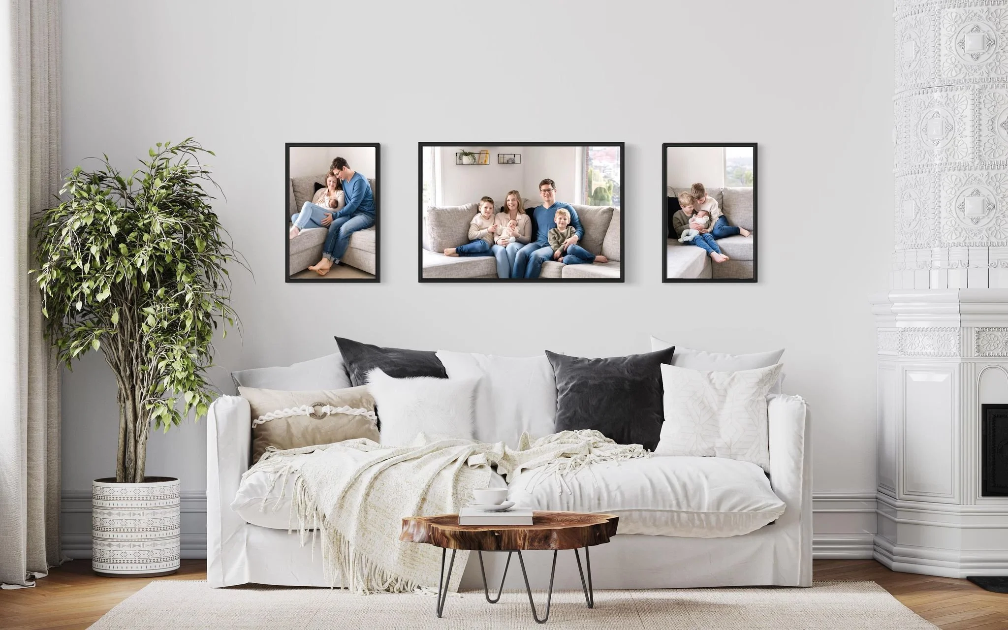 Living room with a white sofa covered with throw pillows and a blanket, a wooden side table, and framed family photos on the wall.