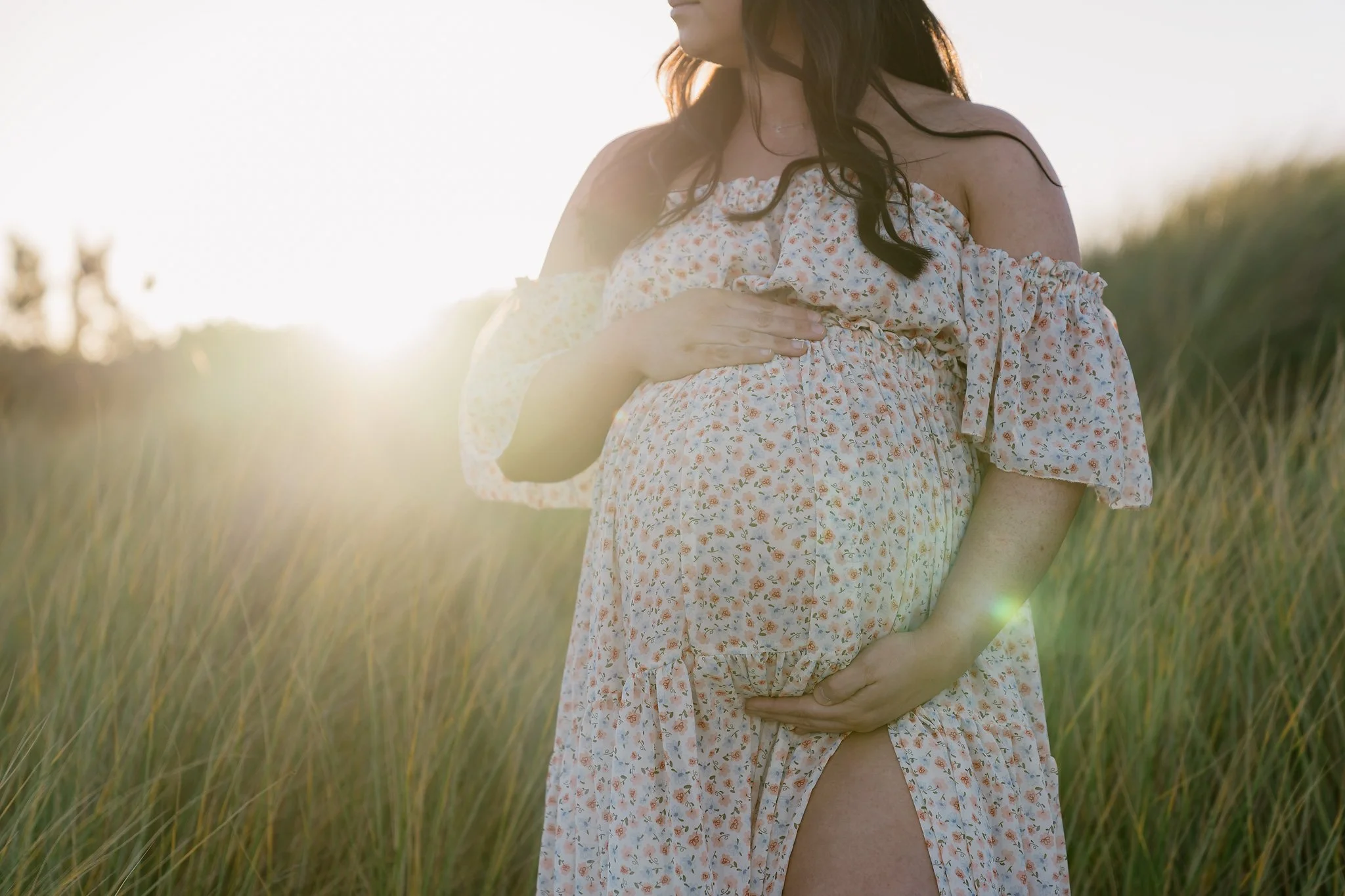 Pregnant woman lifting a smiling toddler in black and white photo.