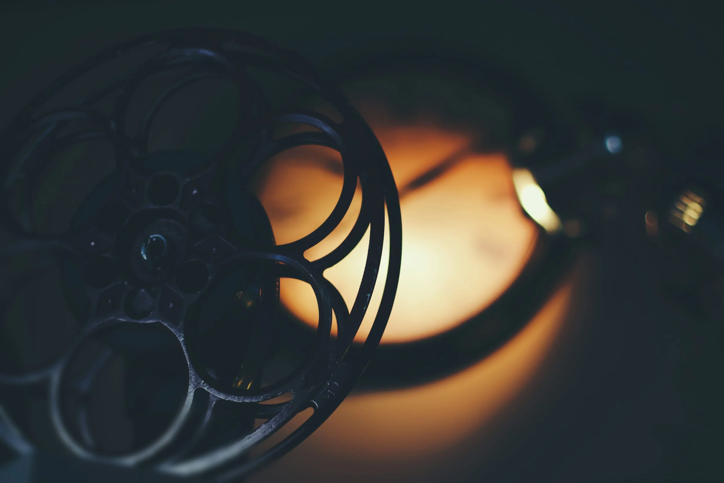 Close-up of rounded metal objects with circular cutouts stacked on top of each other, with a blurry warm light in the background.