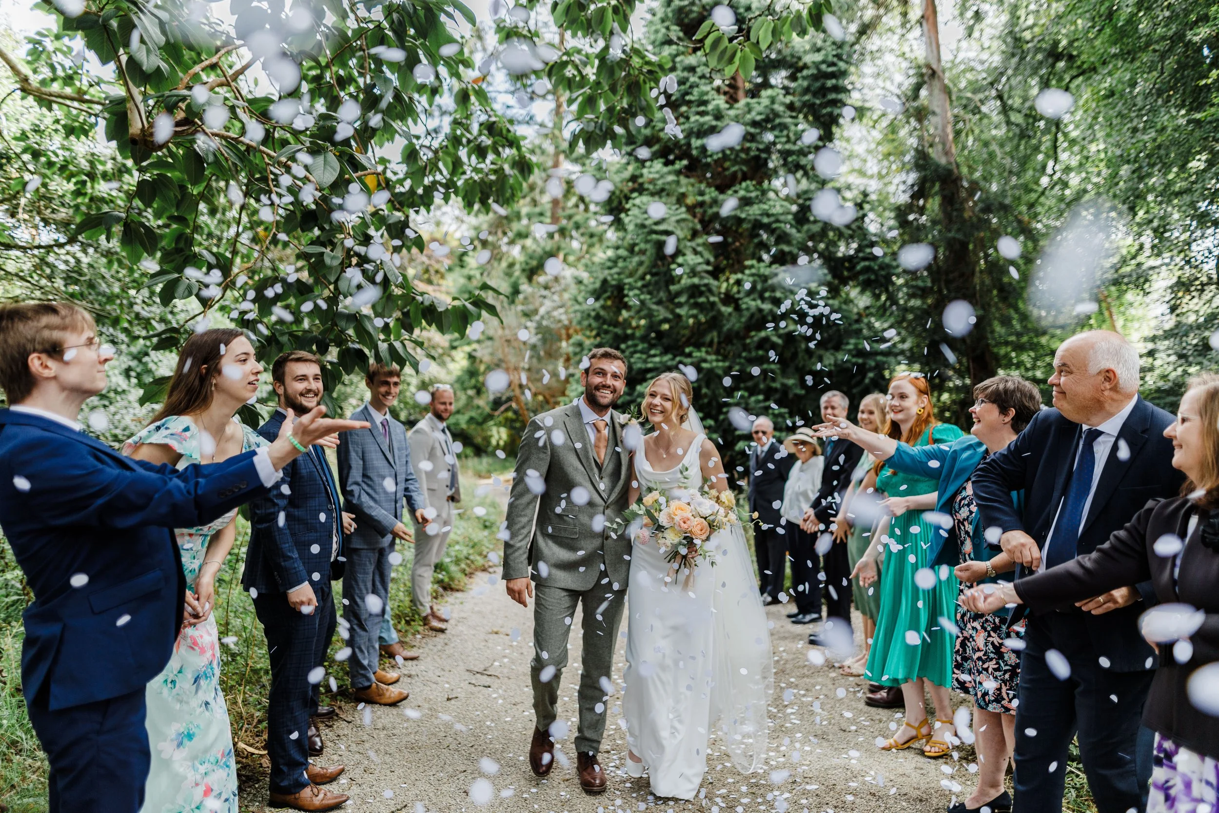 Guests throwing confetti over bride & groom at Scorrier House