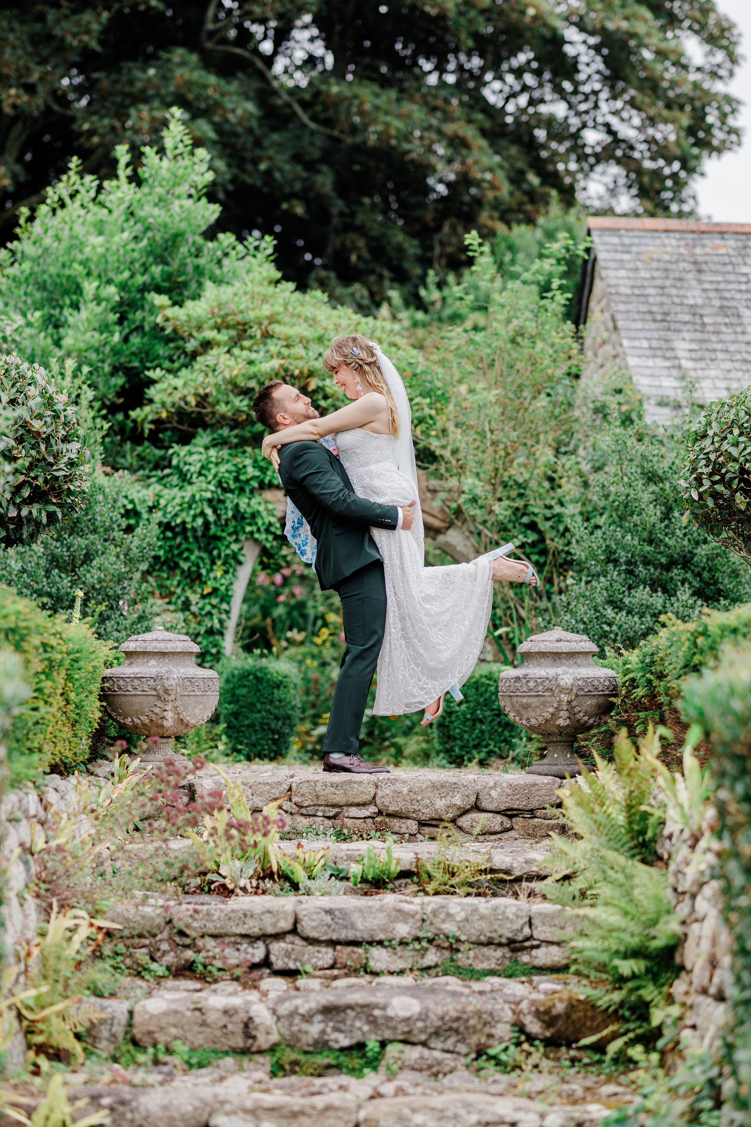 Groom lifting bride on the steps in the gardens at their Pengersick Castle elopement
