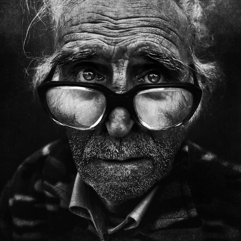 Portrait en noir et blanc d'un homme âgé avec de grosses lunettes.