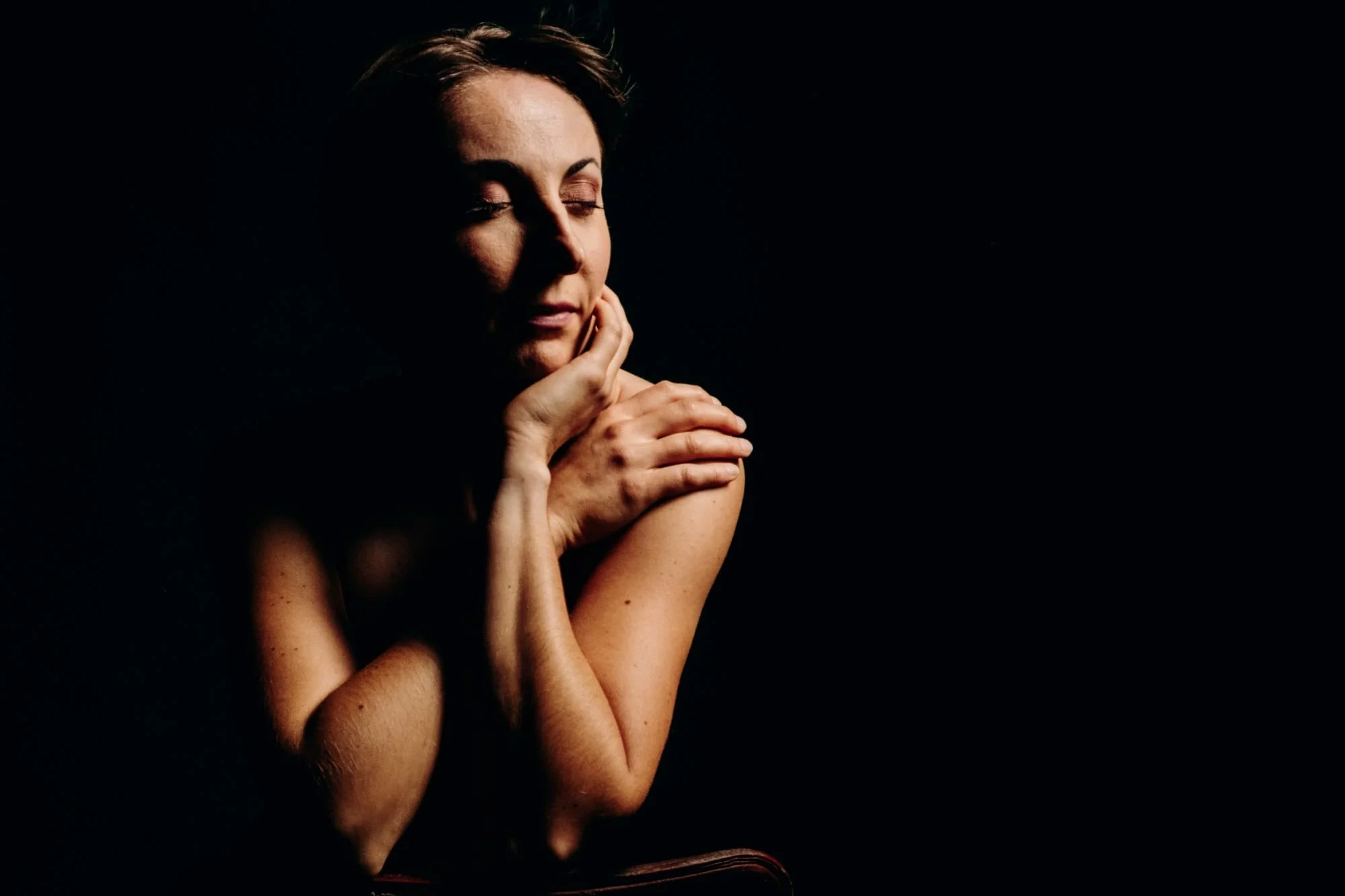 Personne posant dans l'ombre avec les yeux fermés, main sous le menton.