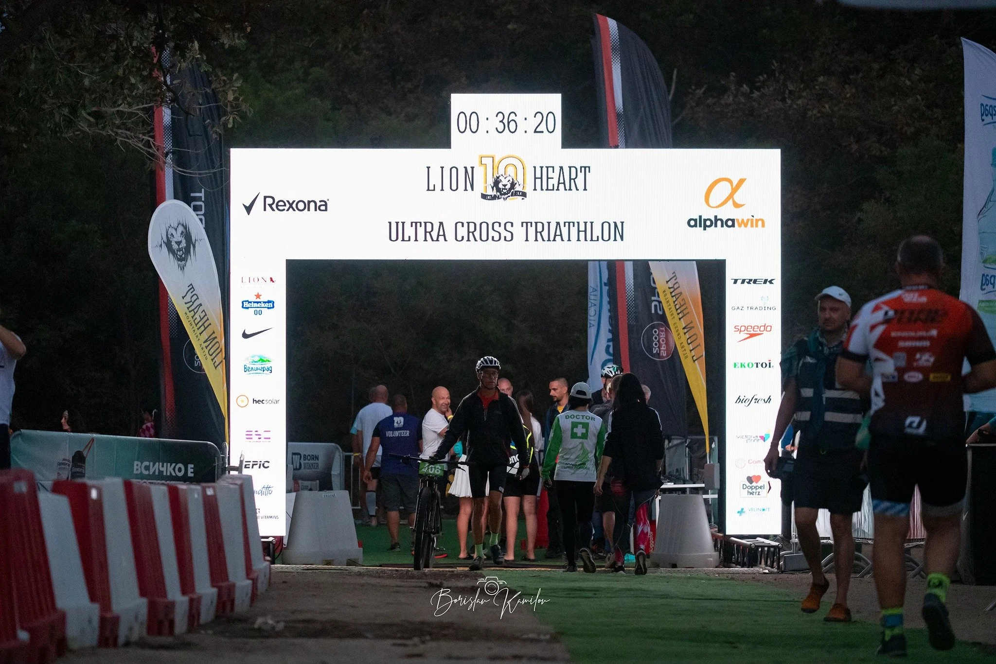 Lion Heart (Лъвско сърце) ultra's start/finish arc lighting up the base camp during dusk - 36 minutes left on the counter for the cut off time, sponsor logos on display.