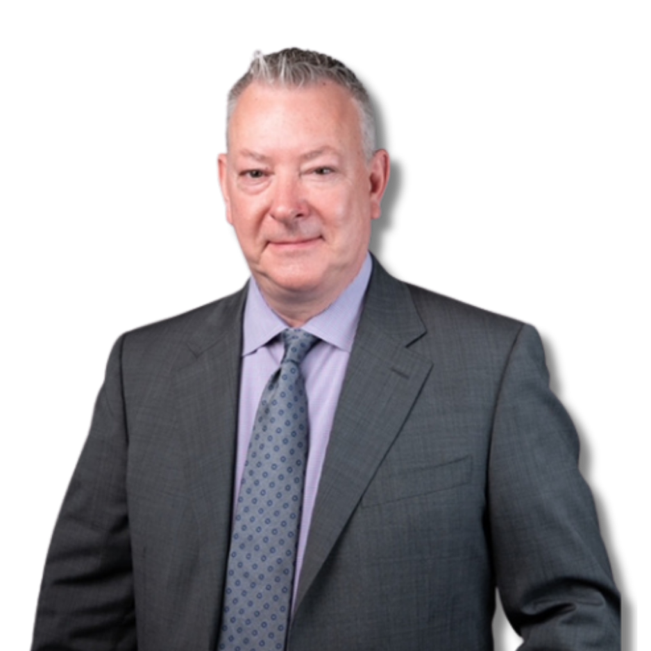 Professional headshot of a middle-aged man wearing a grey suit, light purple shirt, and patterned tie, standing against a neutral grey background and looking directly at the camera.