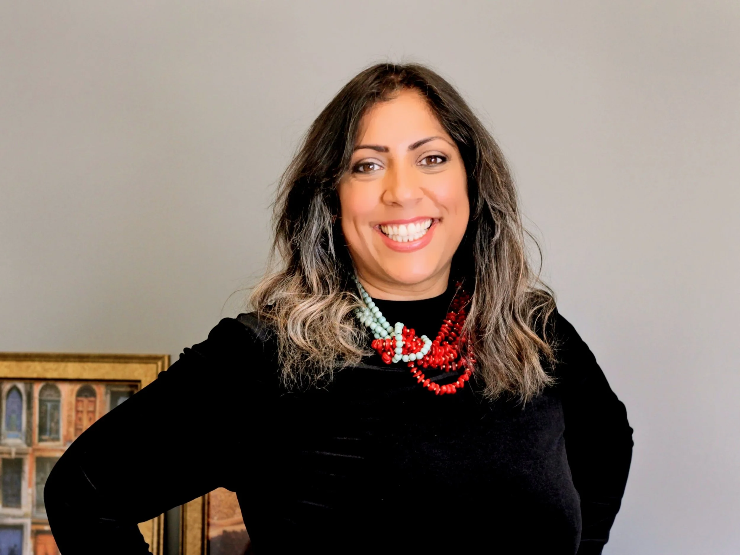 A woman with black hair and blonde highlights wearing a light blue and red beaded necklace