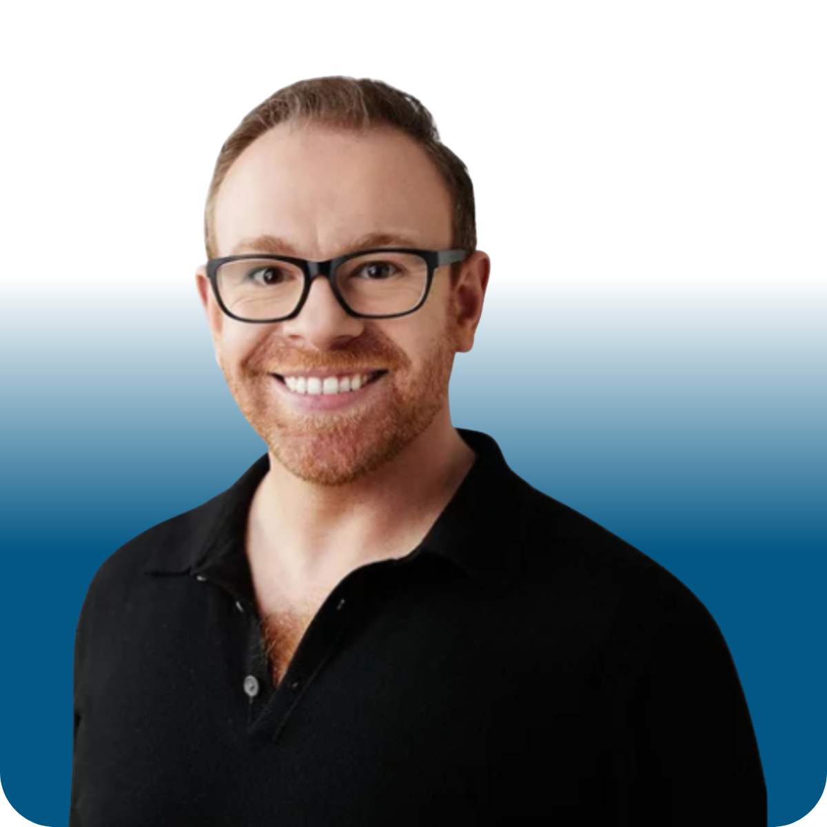 Headshot of a smiling man with glasses, short reddish-brown hair, and a trimmed beard, wearing a black collared shirt, against a gray background.