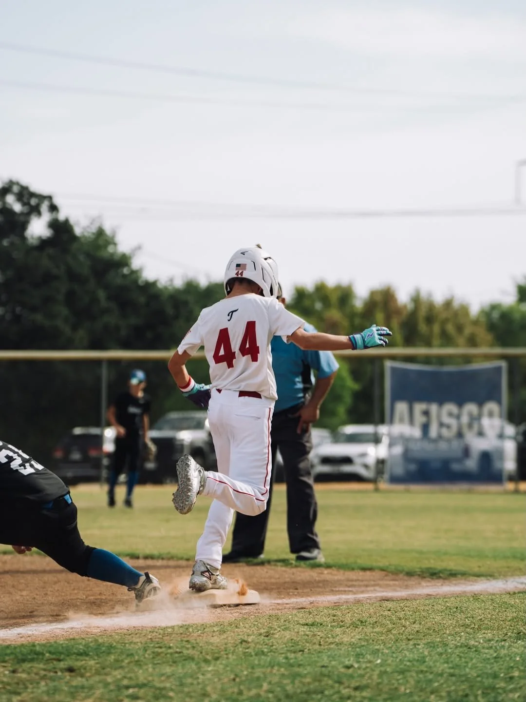 Travelers player running the bases with teammates watching